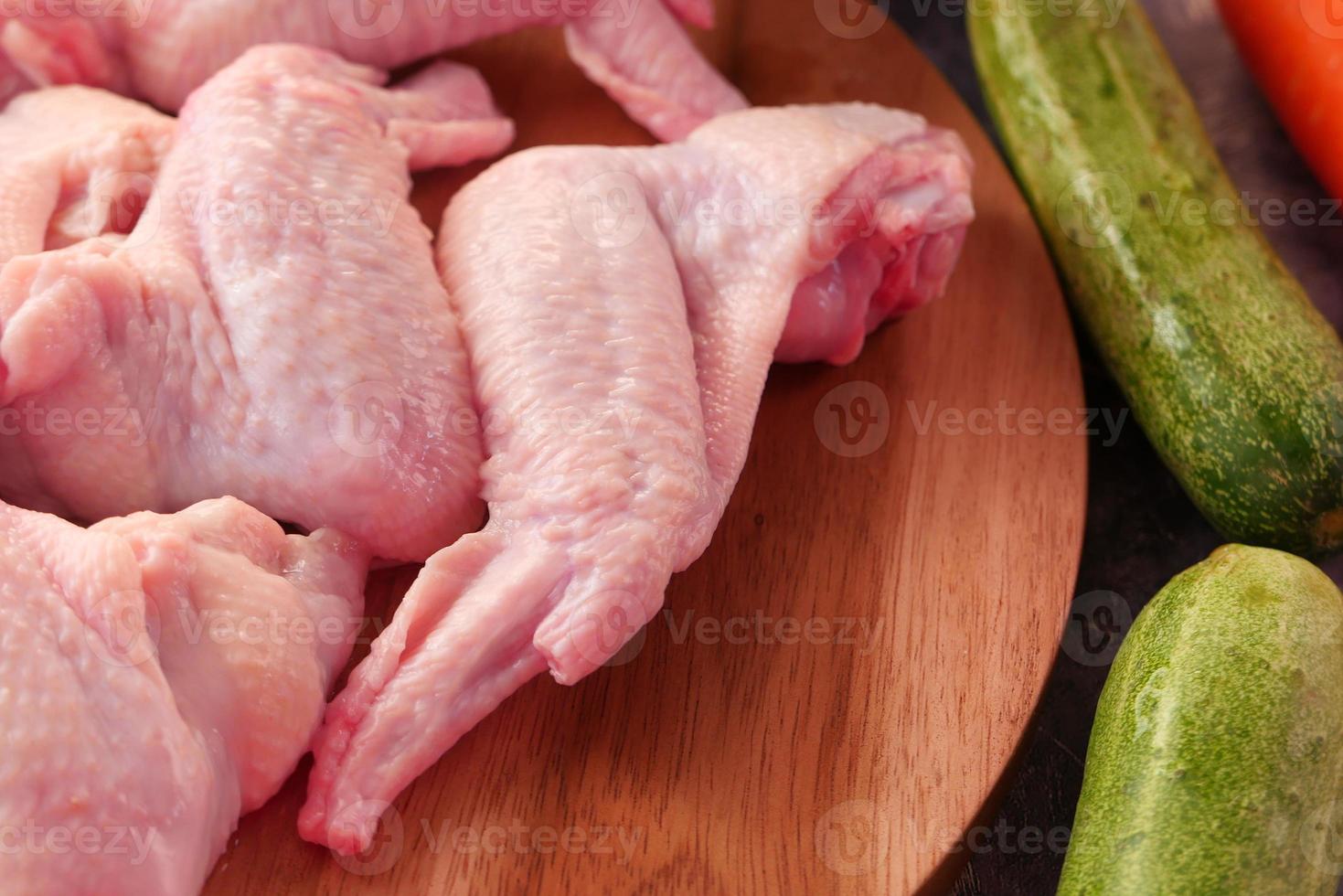 ali di pollo crude con verdure su un tavolo foto