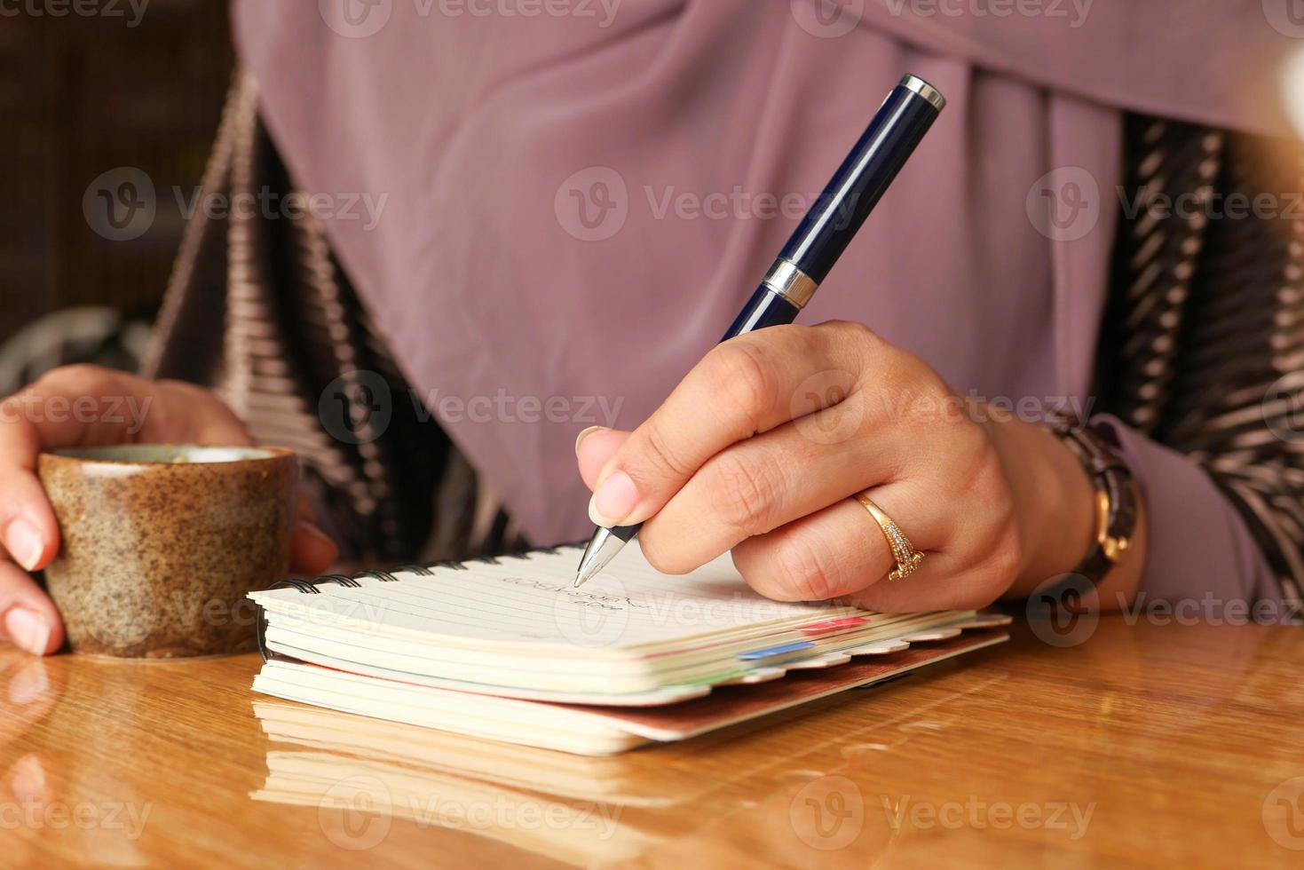 stretta di mano della donna che scrive sul blocco note foto