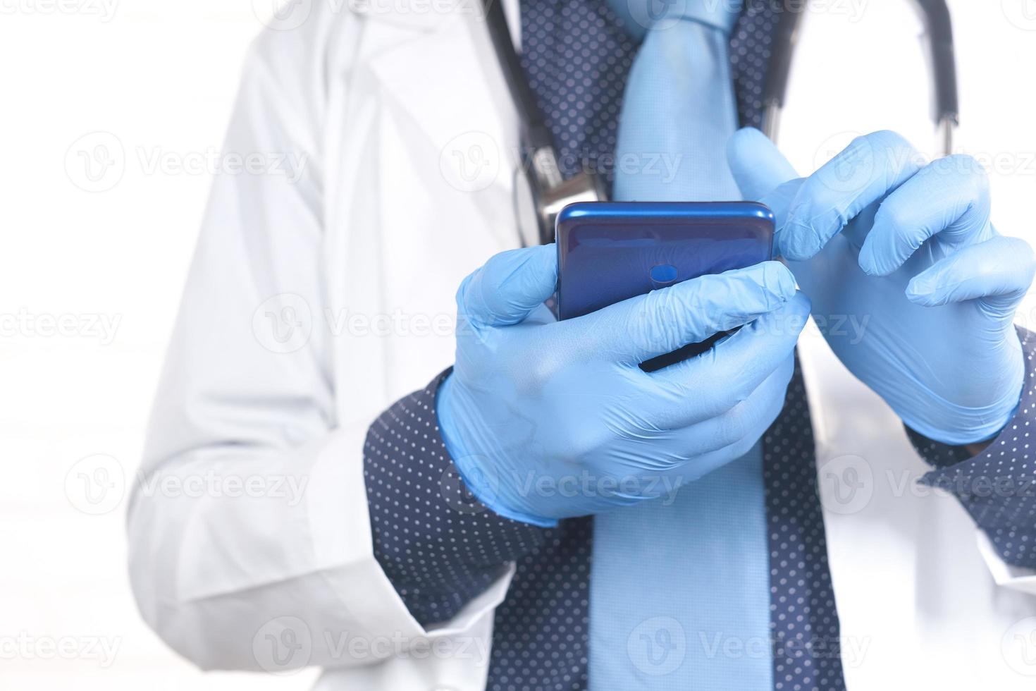 mani del medico in guanti protettivi utilizzando uno smartphone foto