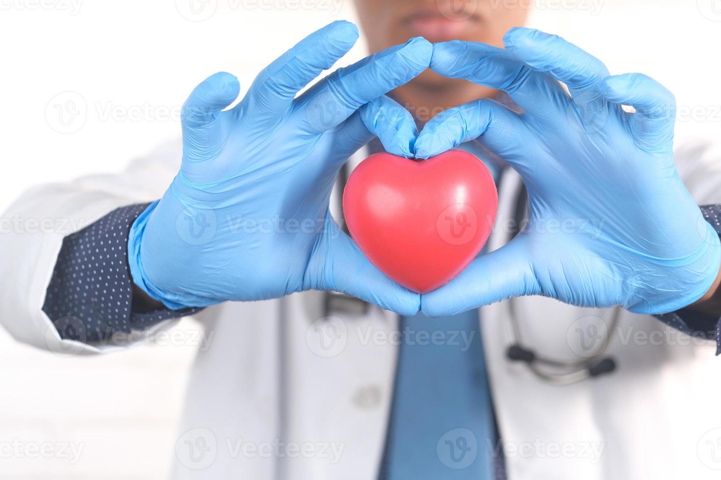 mano del medico in guanti protettivi che tengono cuore rosso foto