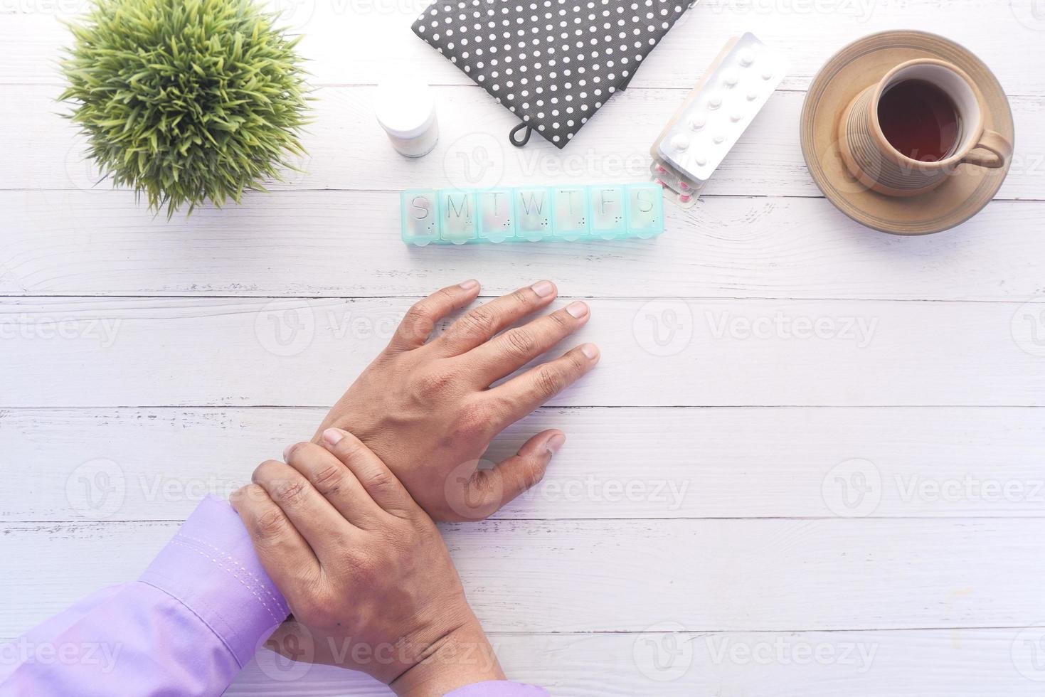 le mani dell'uomo sul tavolo con medicina e caffè foto