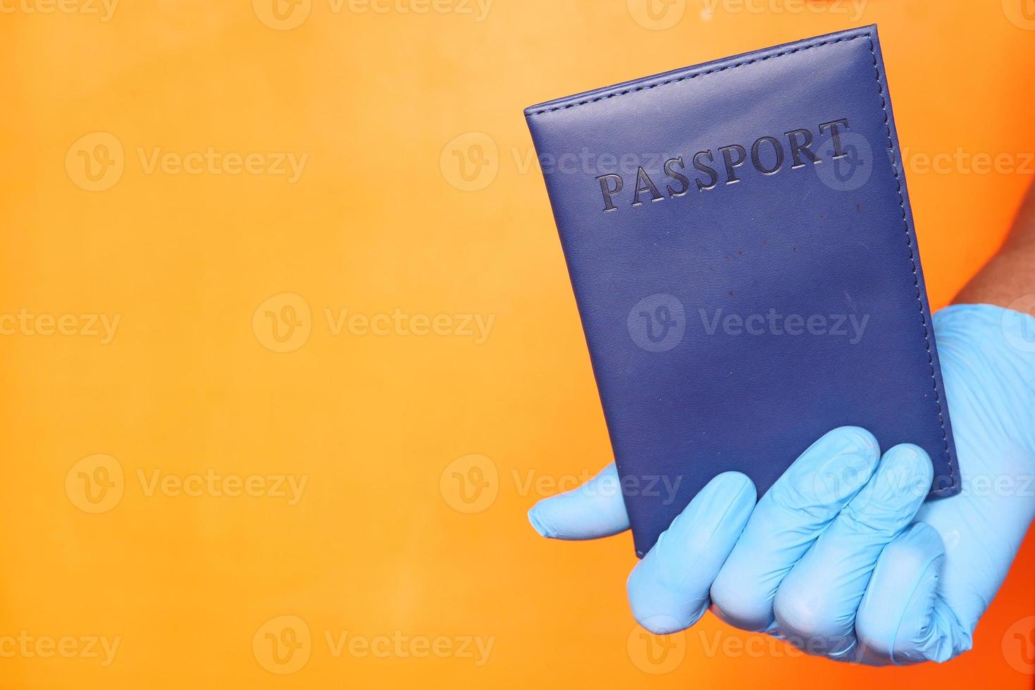 mano in guanti chirurgici blu che tengono il passaporto foto