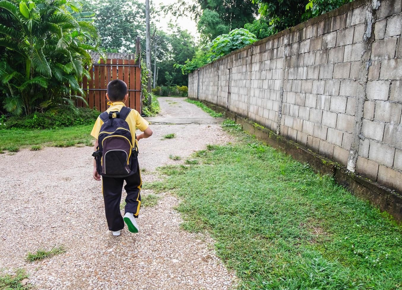 ragazzo che va a scuola a piedi con uno zaino foto