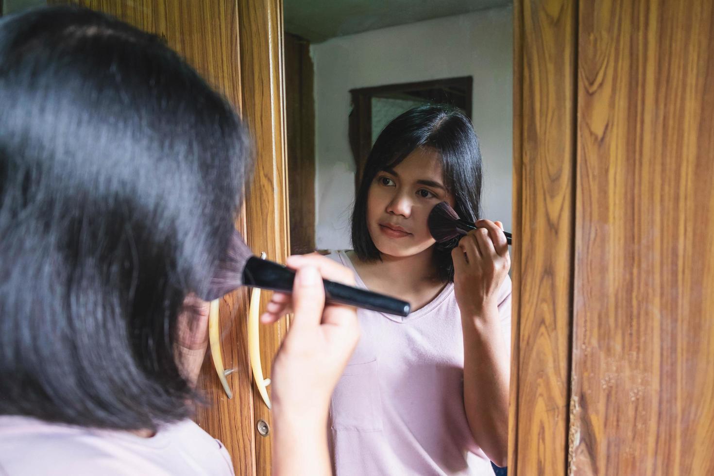 donna che applica arrossire in uno specchio foto