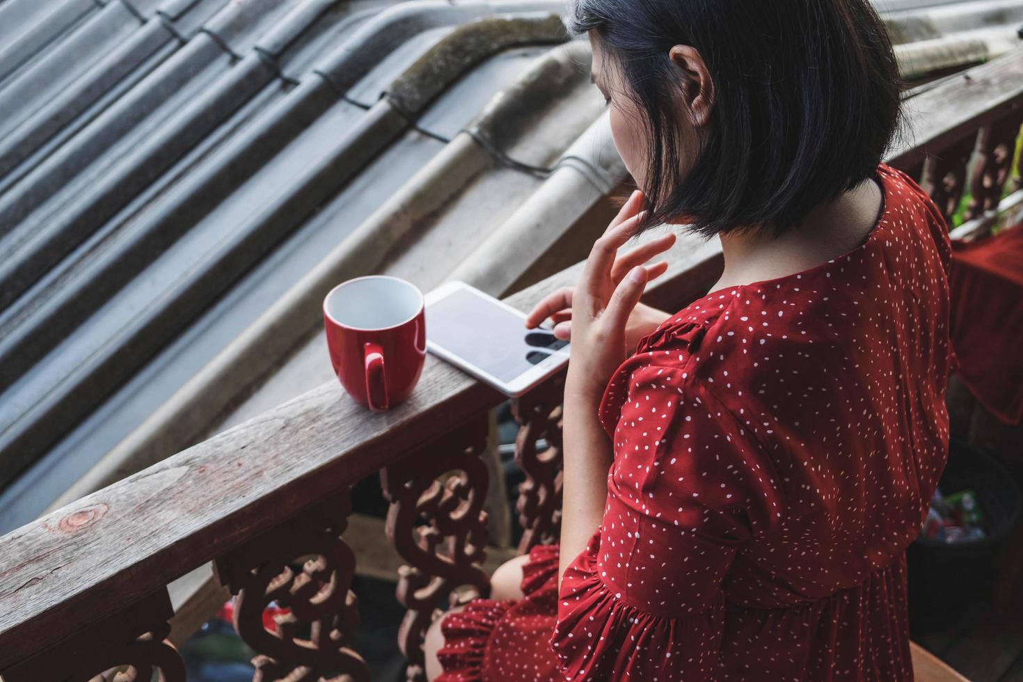 donna seduta con un caffè e telefono su una terrazza foto