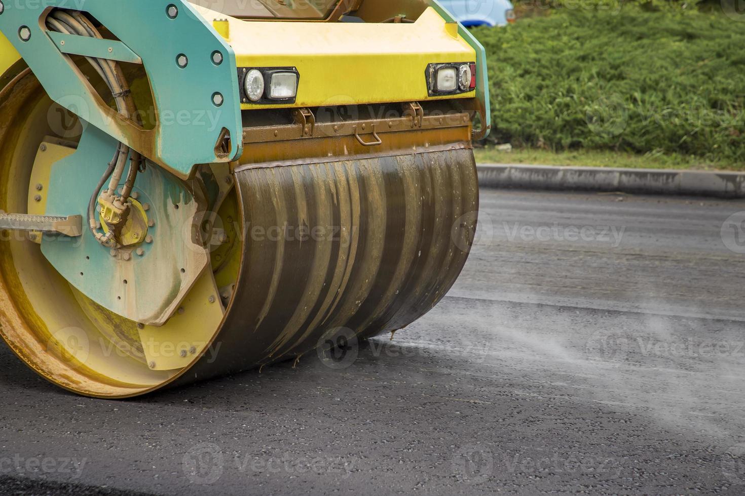 vicino Visualizza di tamburo rullo a il costruzione luogo, Lavorando su il nuovo strada con Fumo foto