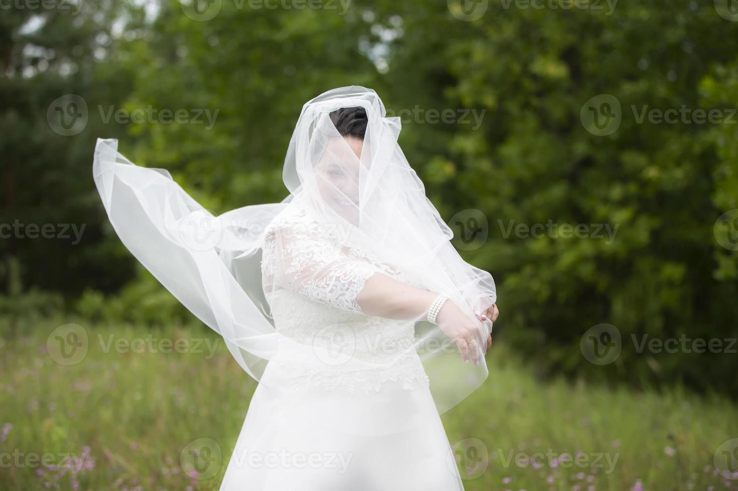 il Grasso sposa nascosto nel un' nozze velo contro il fondale di natura. foto