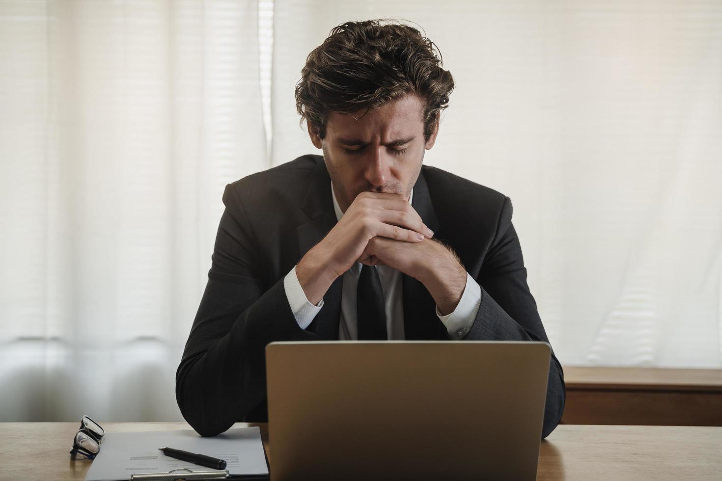 dipendente esausto, stressato caucasico giovane attività commerciale uomo Tenere mani e vicino il occhi quando Lavorando, soffrire su difficile opera mentre utilizzando il computer portatile computer a ufficio. col tempo lavoro, debito problema. foto