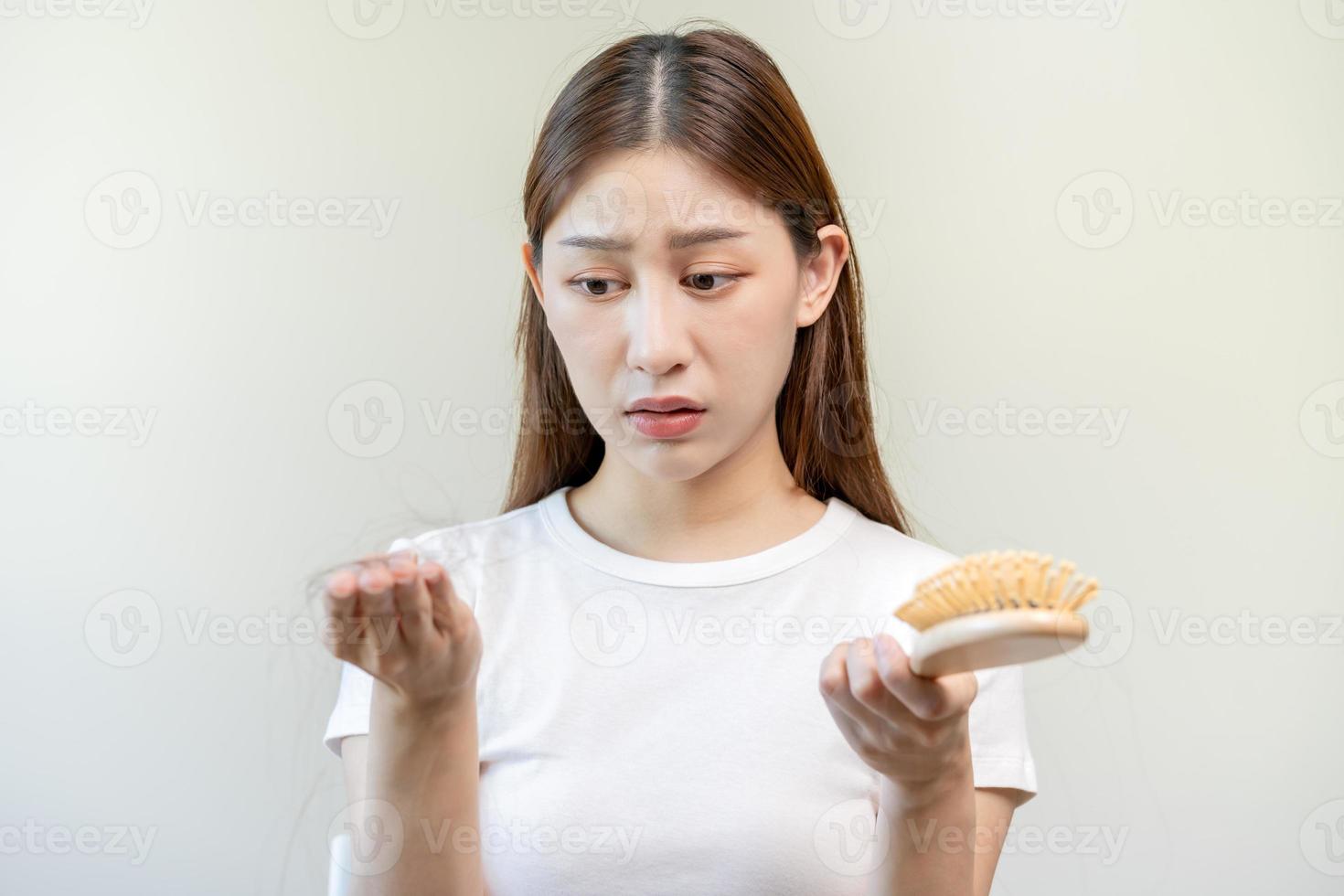 serio, preoccupato asiatico giovane donna, ragazza Tenere pettine, mostrare sua spazzola per capelli con lungo perdita capelli problema dopo spazzolatura, capelli autunno su problema. Salute cura, bellezza con copia spazio su bianca sfondo. foto