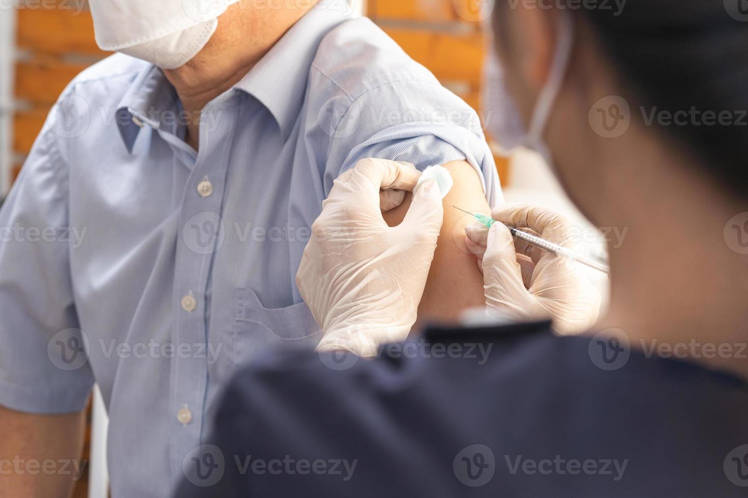 covid-19,coronavirus, anziano asiatico adulto uomo ottenere vaccino a partire dal medico o infermiera dando tiro per maturo paziente a clinica. assistenza sanitaria, immunizzazione, malattia prevenzione contro influenza o virus pandemia. foto