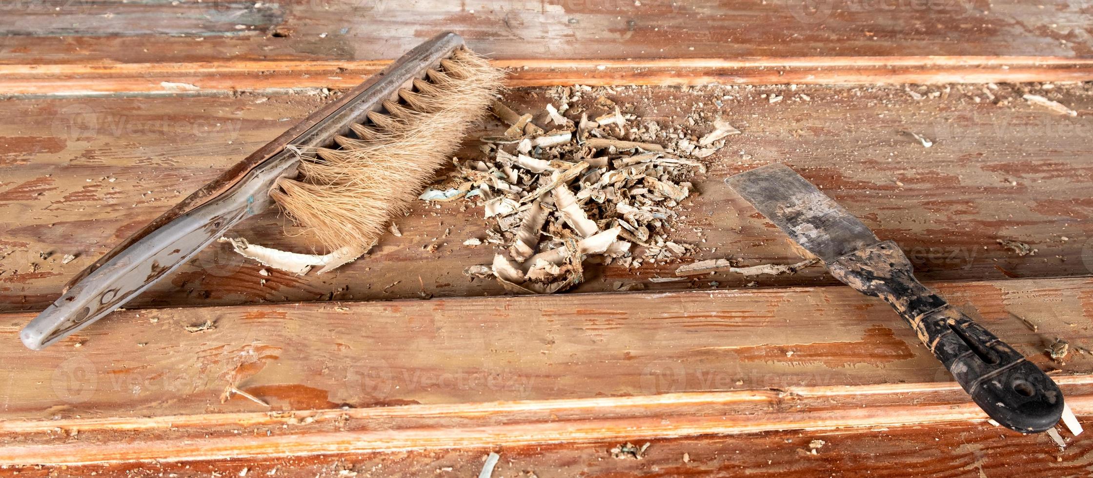 spatola e pennello con trucioli di legno rotti su un tavolo di legno foto