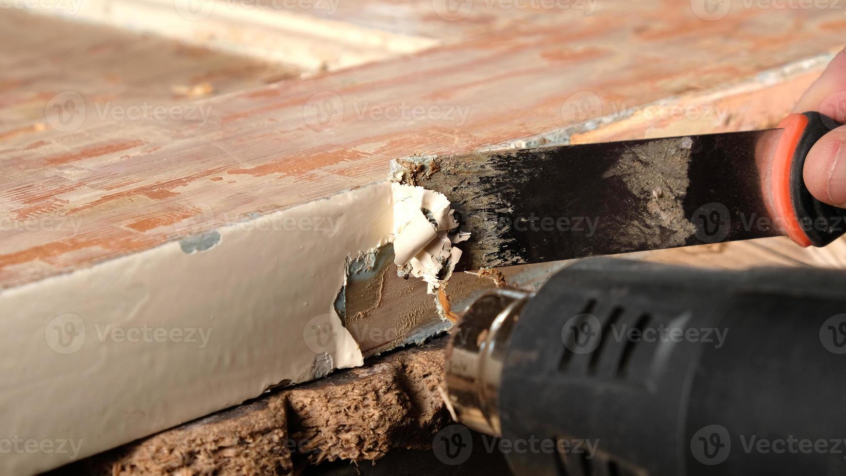 mani che puliscono vecchia vernice da una porta di legno, restauro di mobili in legno foto