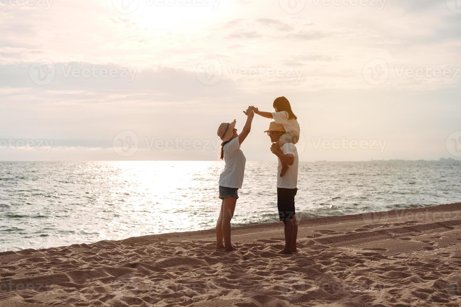 contento asiatico famiglia godere il mare spiaggia a consistente padre, madre e figlia avendo divertimento giocando spiaggia nel estate vacanza su il oceano spiaggia. contento famiglia con vacanze tempo stile di vita concetto. foto