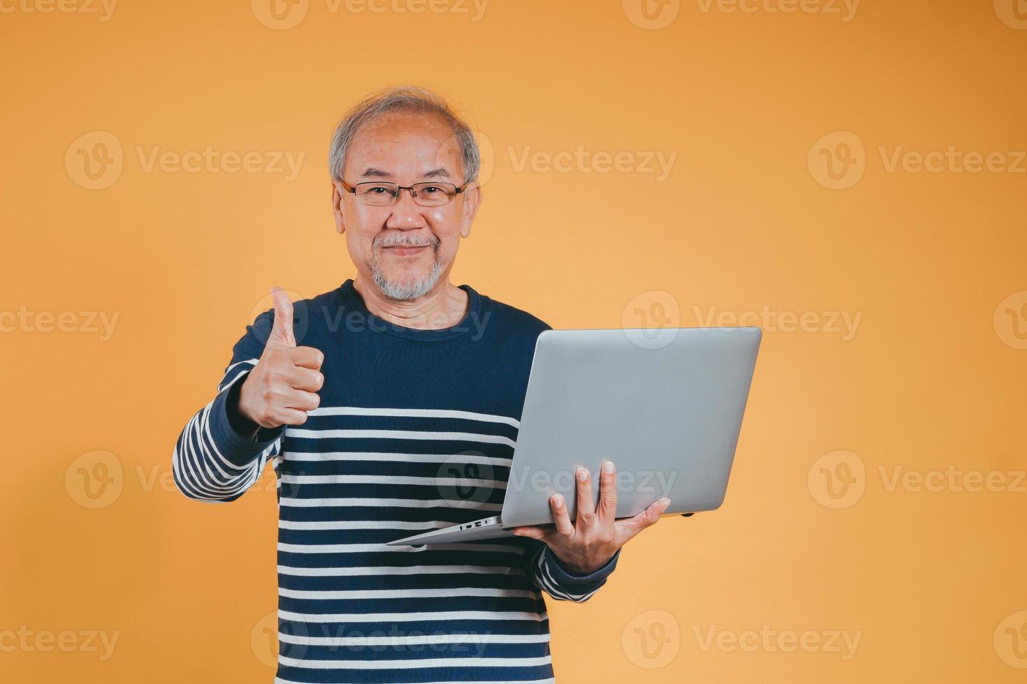 asiatico anziano uomo utilizzando il computer portatile computer per Lavorando dopo la pensione su il giallo sfondo. foto