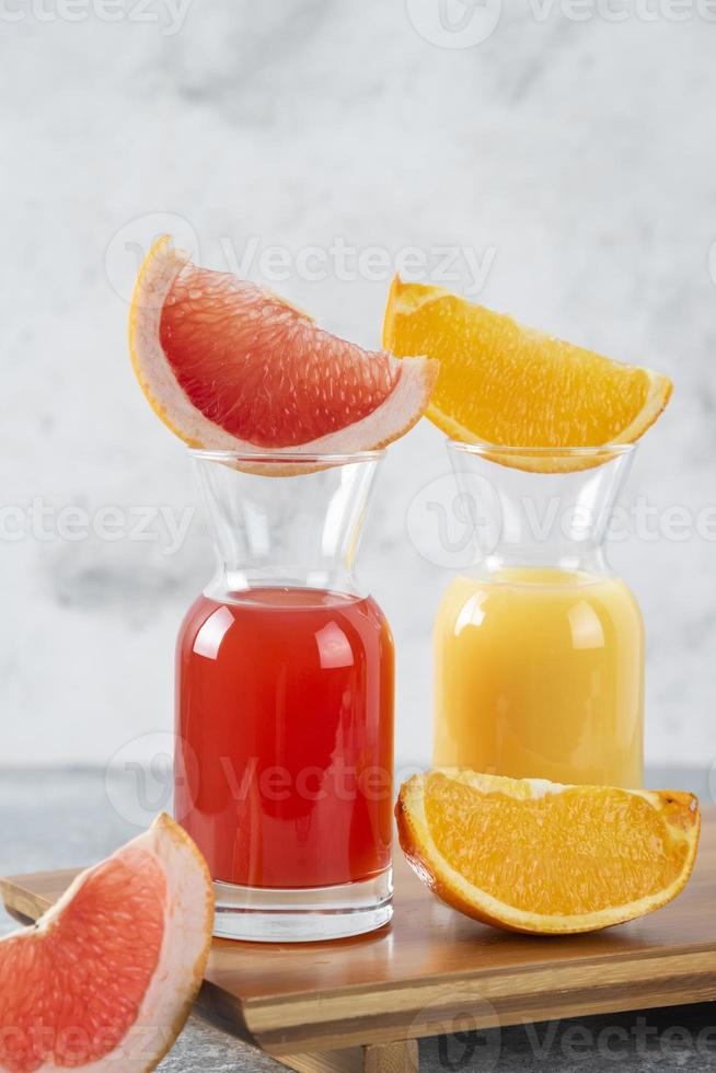 due bicchieri di pompelmo e succo d'arancia su uno sfondo di pietra foto