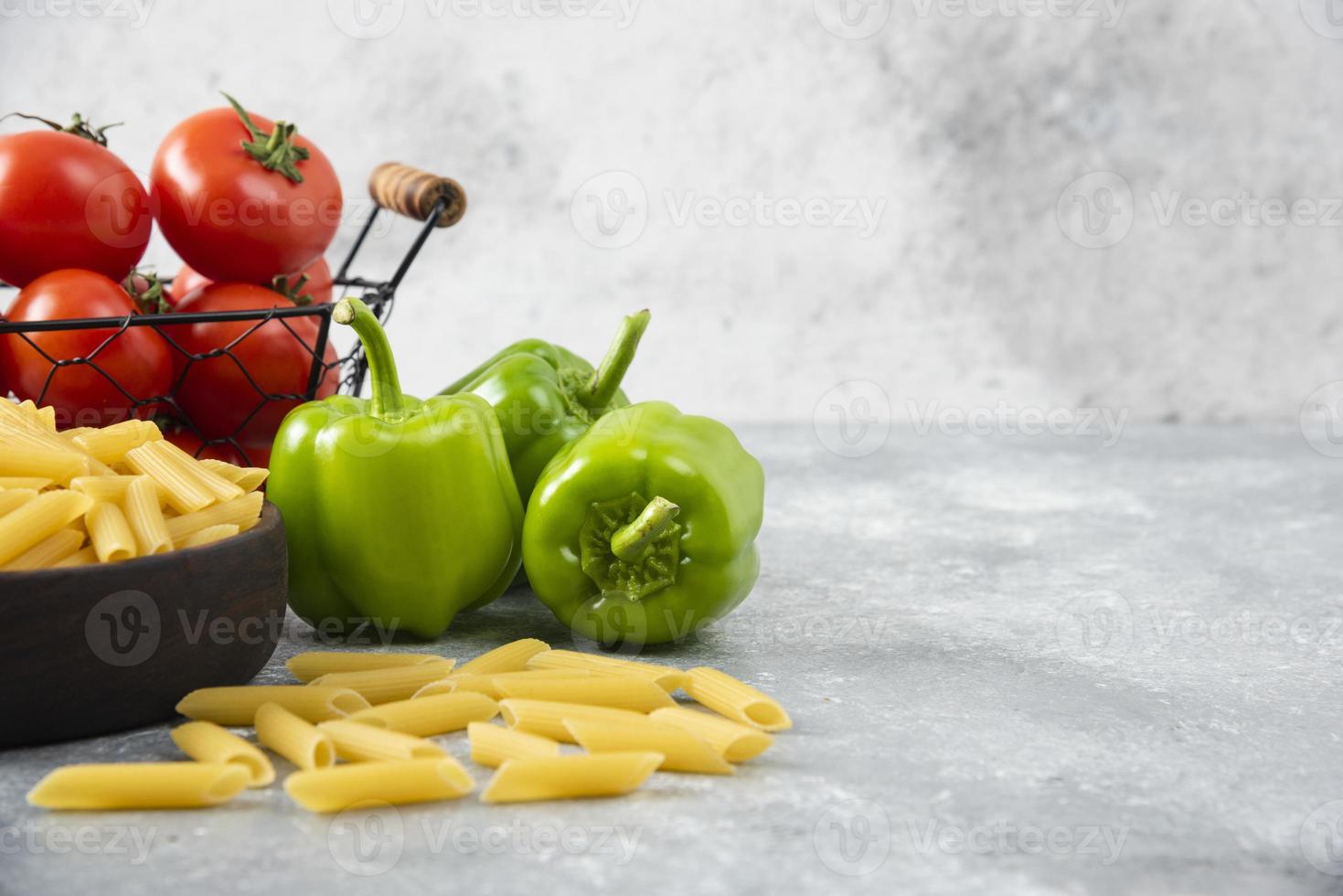 pasta cruda con verdure fresche mature poste su un tavolo di pietra foto