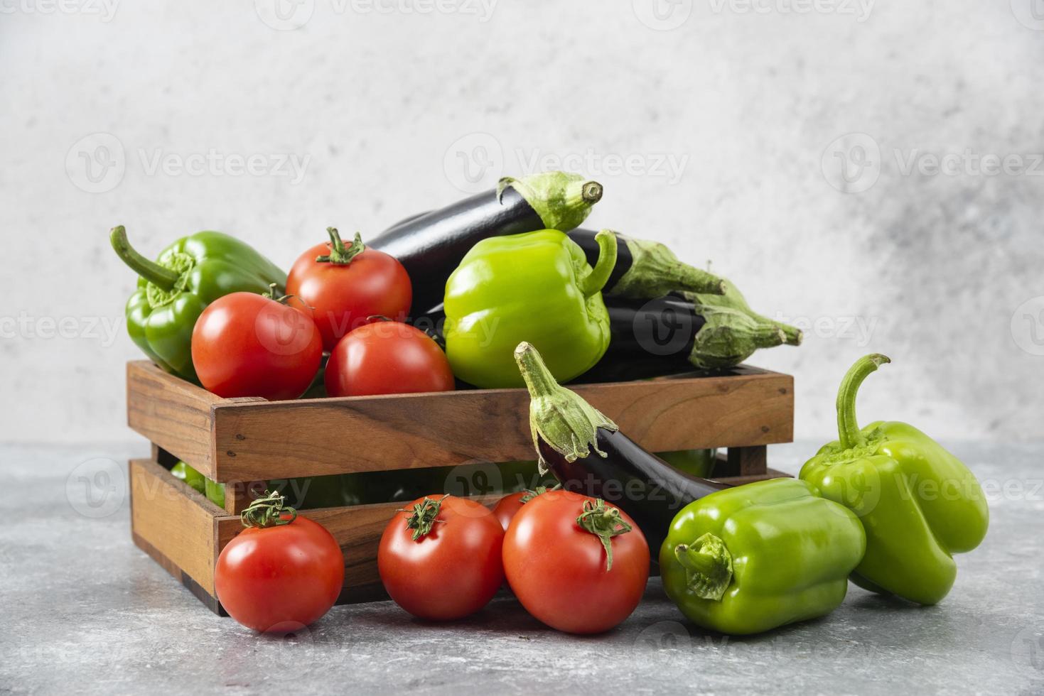 scatola di legno piena di verdure fresche mature poste su uno sfondo di pietra foto