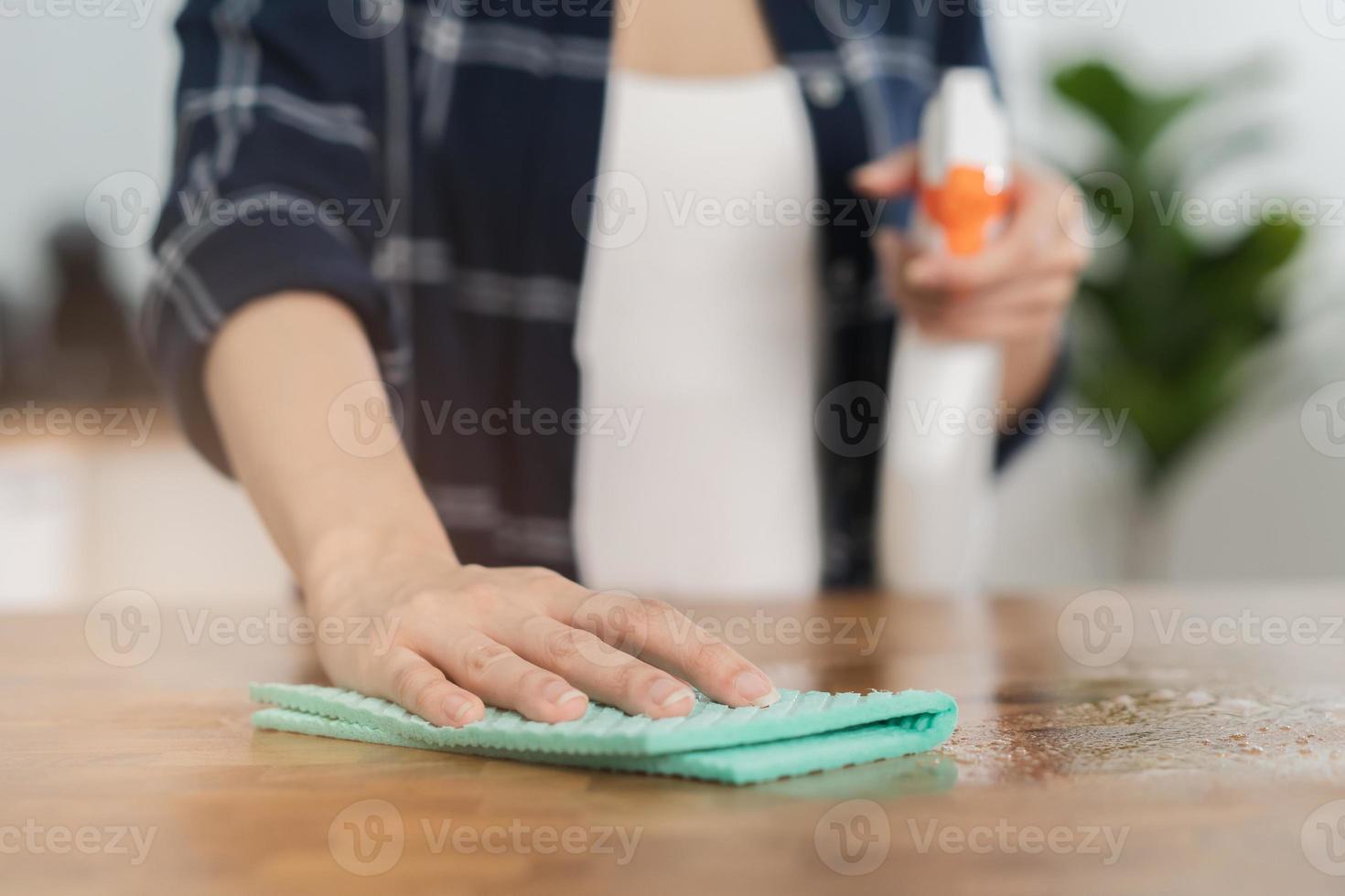 mano di asiatico giovane donna mano pulizia di legno tavolo, mobiletto, utilizzando straccio strofinare polvere, Tenere spray bottiglia nel cucina a casa. domestico igiene pulito su, addetto alle pulizie le persone, attrezzatura o attrezzo per pulizia. foto