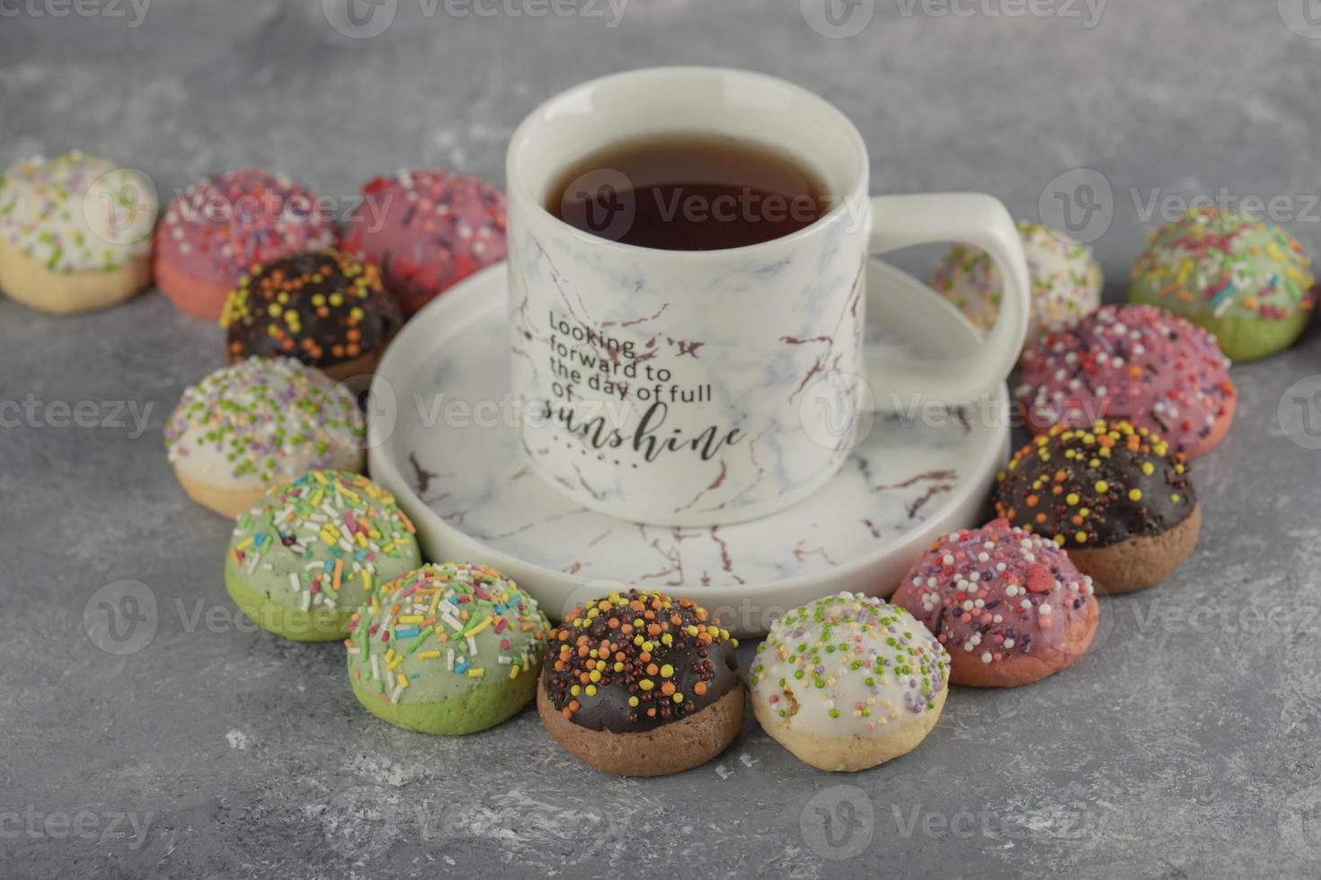 ciambelle dolci colorate con codette e una tazza di tè foto