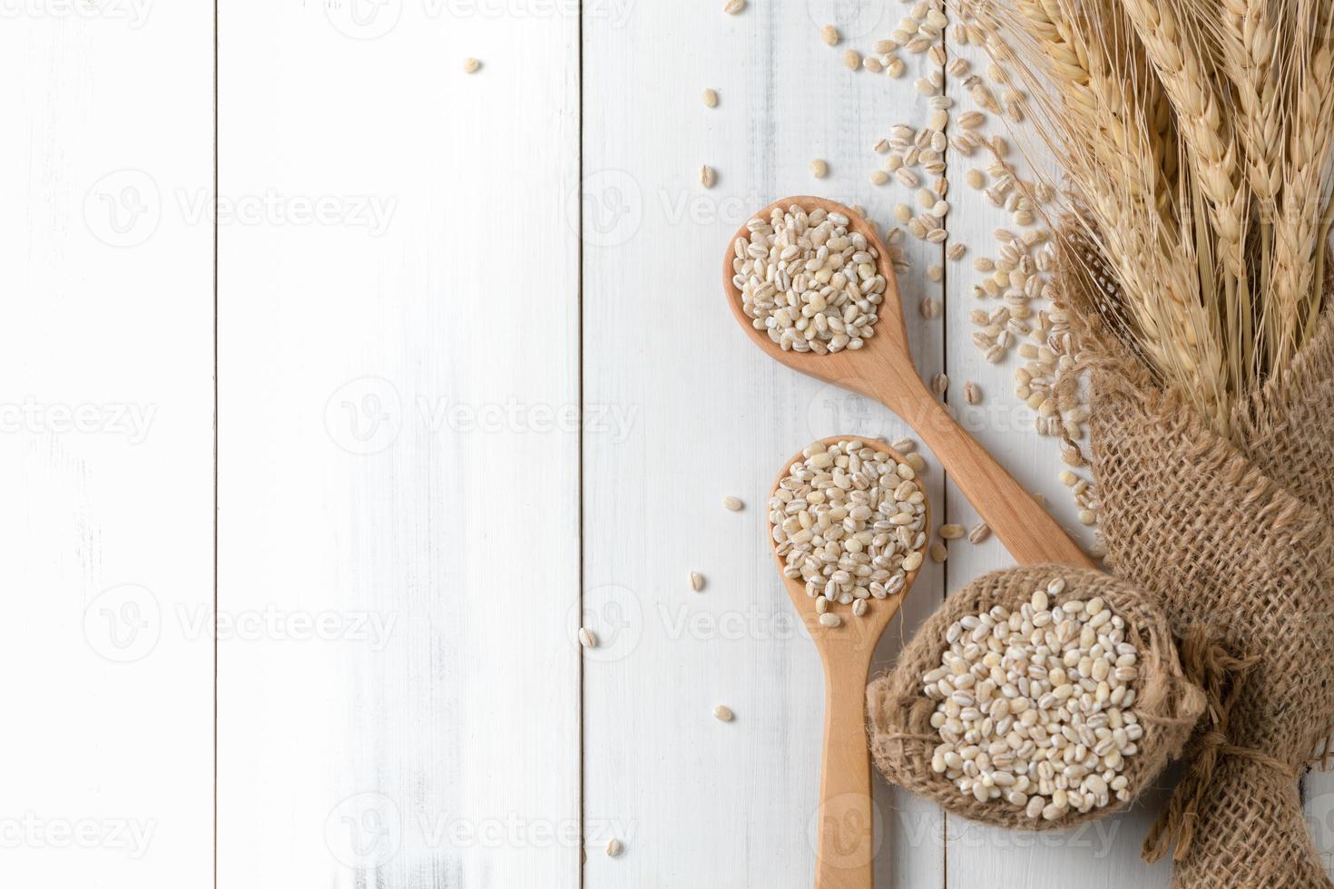 mucchio di perla orzo su legna cucchiaio con orecchio di orzo foto