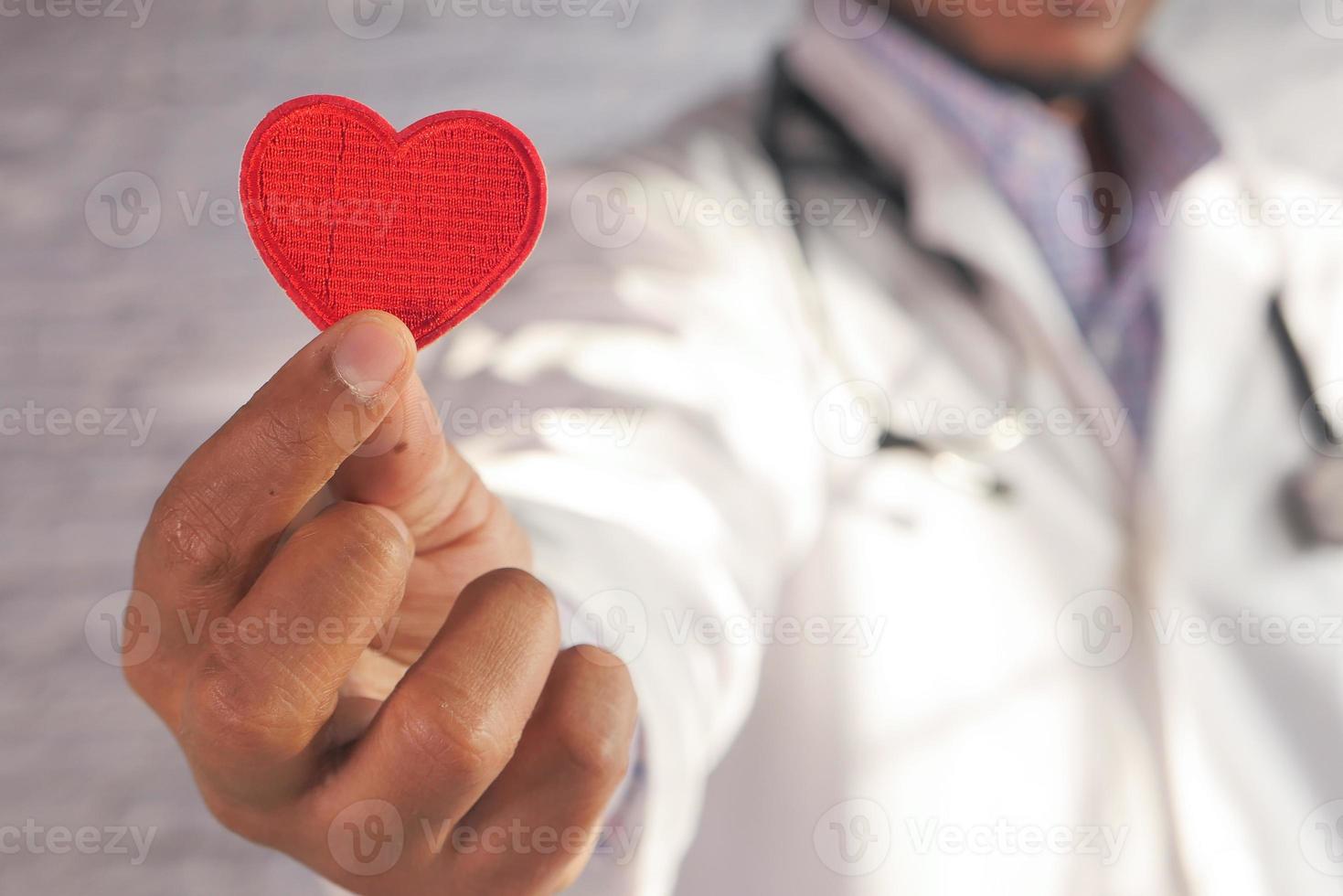 medico che tiene un cuore rosso del giocattolo foto