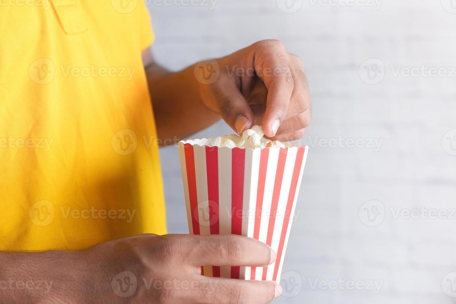 uomo in camicia gialla che mangia popcorn foto