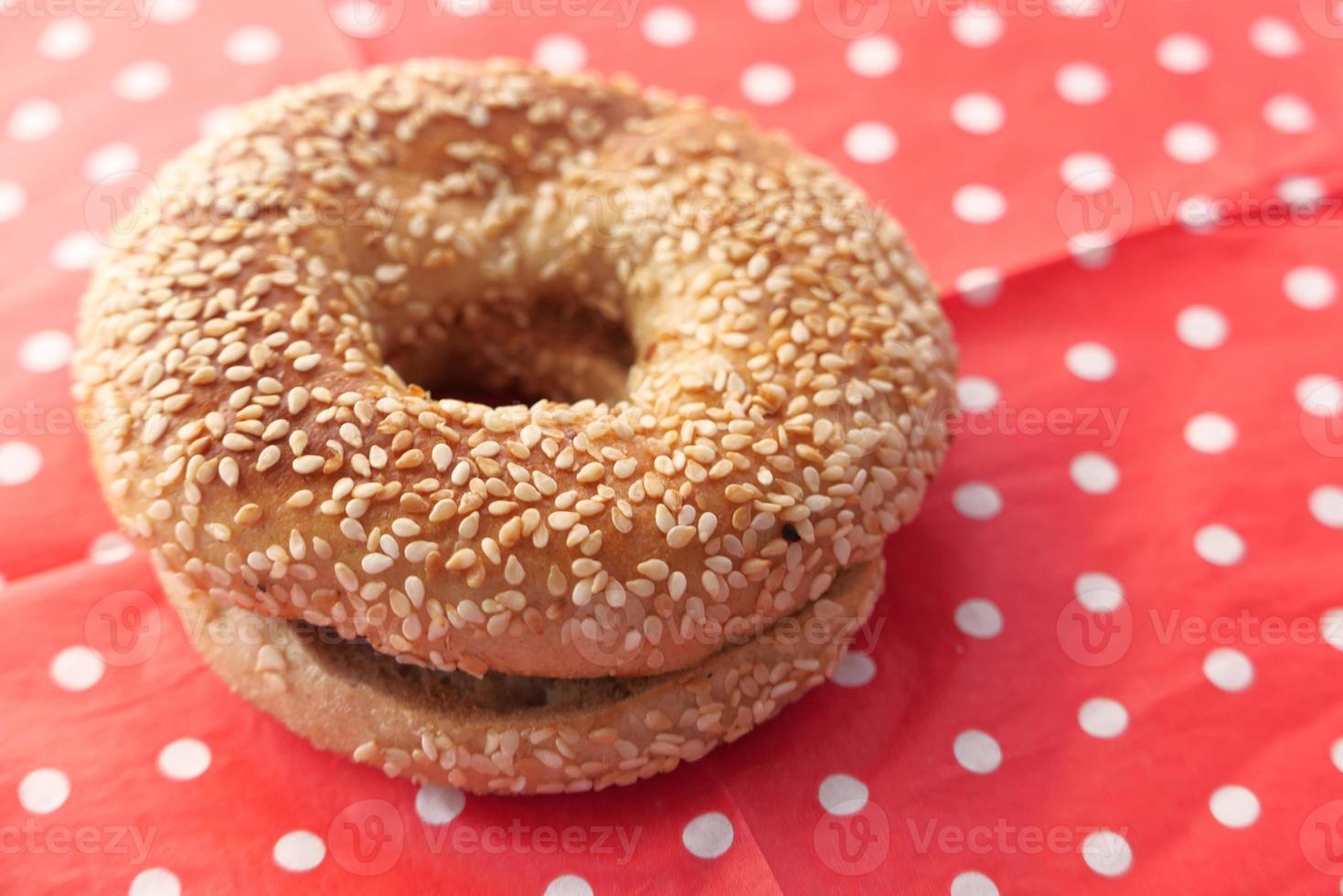 bagel fresco con semi di sesamo su tovaglia a pois foto