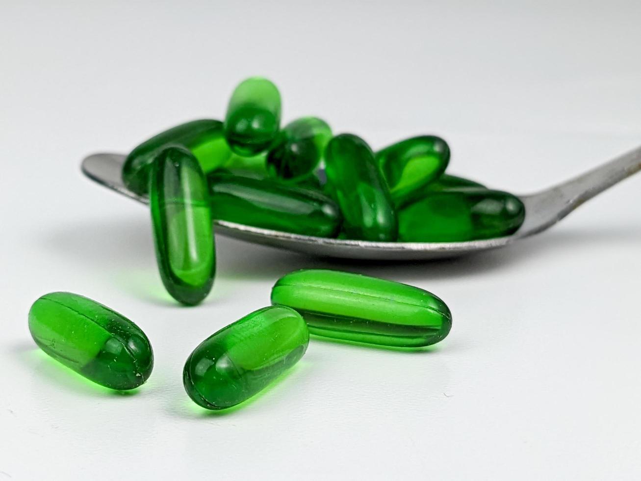 verde trasparente capsula pillole con cucchiaio. Salute cura concetto foto