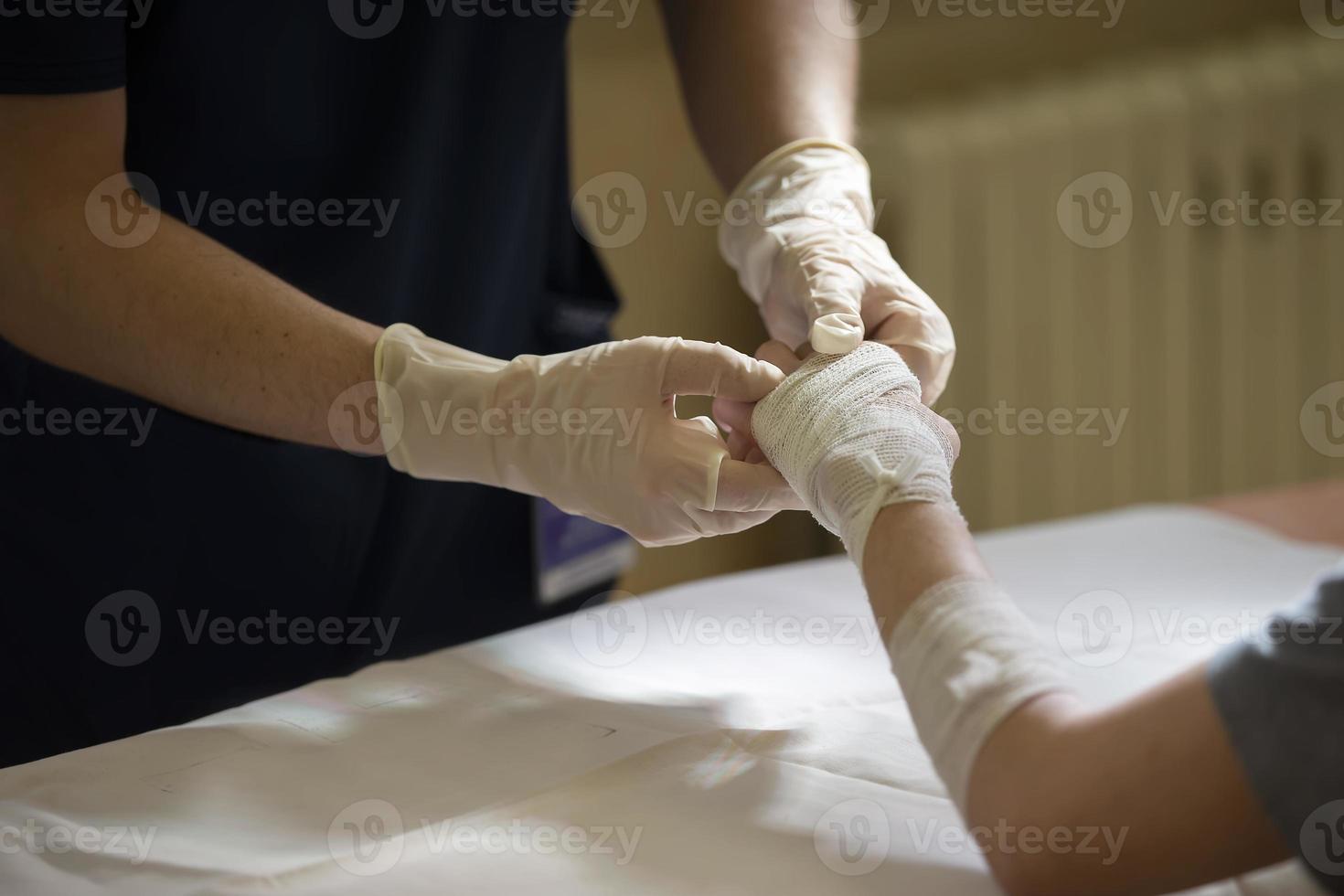 il medico cravatte il del paziente mano con un' medico bendare. foto