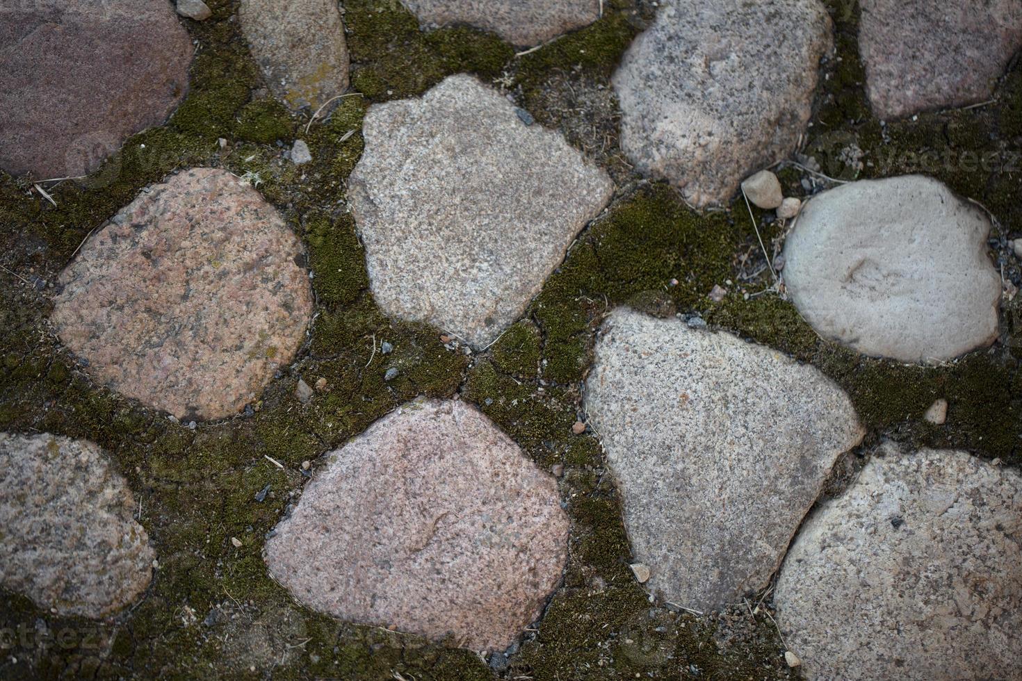 sfondo di un vecchio parete fatto di ruvido grande pietre, massi e muschio. foto
