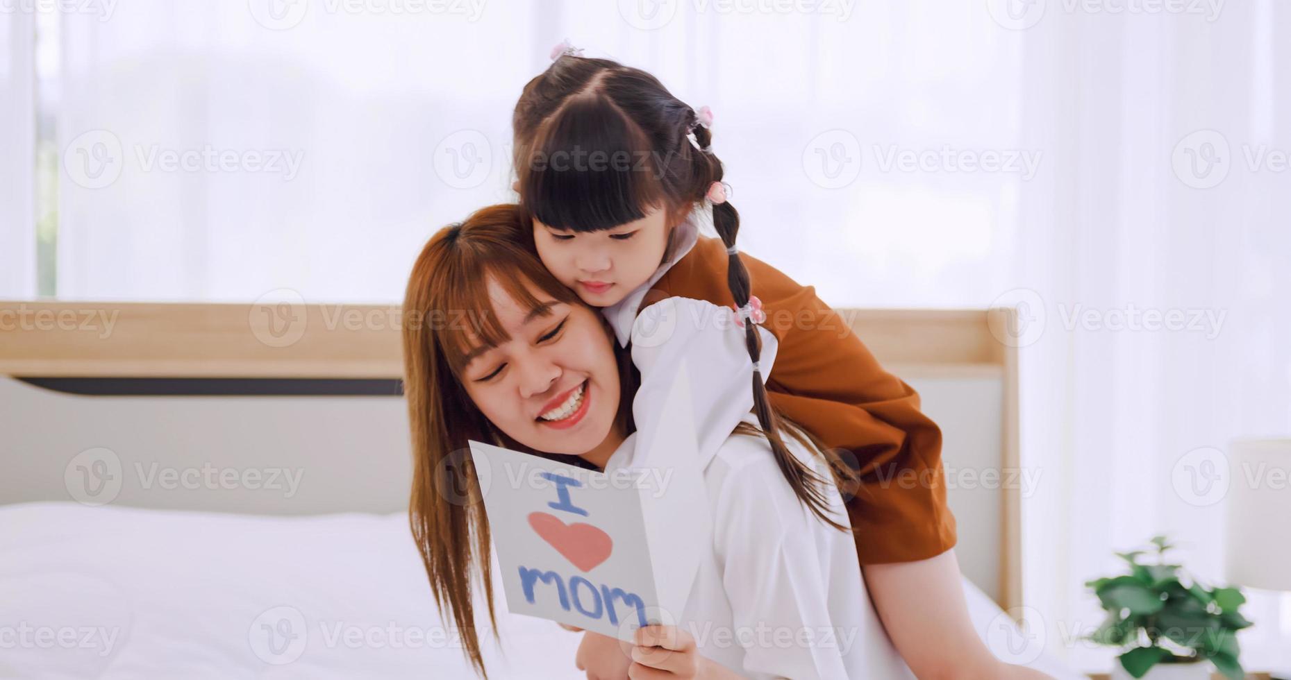 un' poco figlia dando mamma fatto a mano saluto carta e desiderando sua contento La madre di giorno. foto