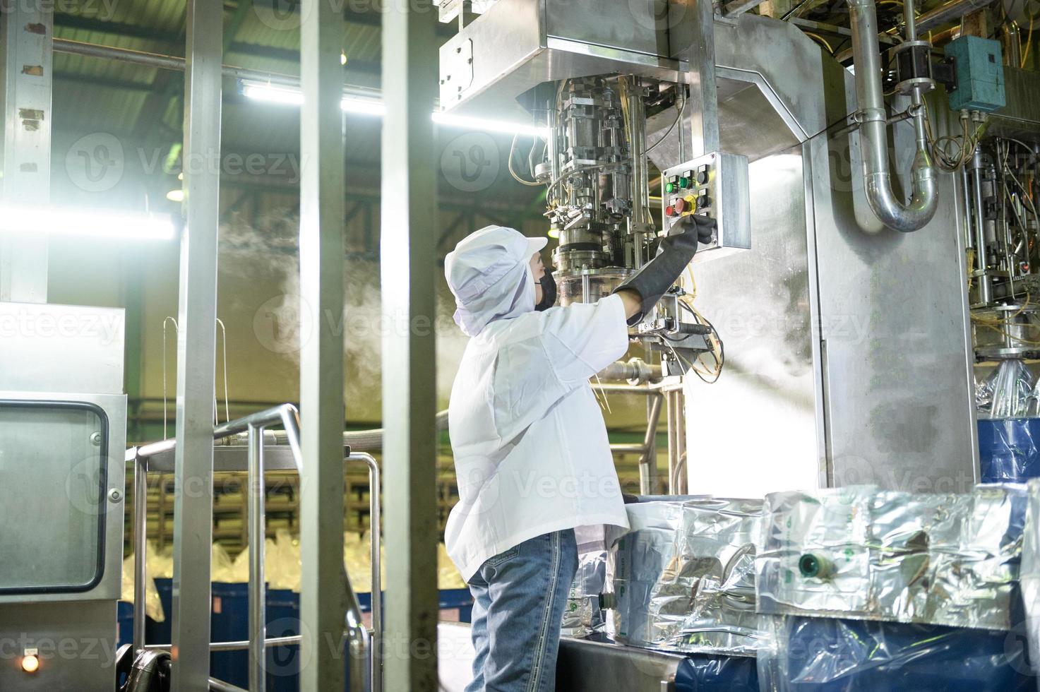 femmina lavoratore nel un' ketchup fabbrica controllato automatico asettico Riempimento macchina Riempimento ketchup in grande tini a un industriale servizio, struttura nel Asia. cibo industria agroindustria. foto