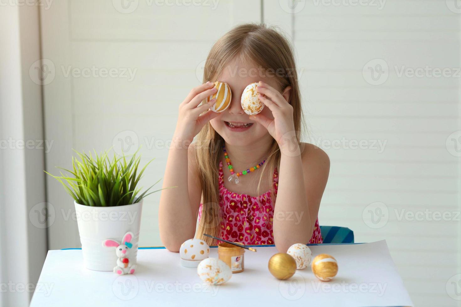 mano poco ragazza pittura modelli uova con oro dipingere. contento Pasqua. foto