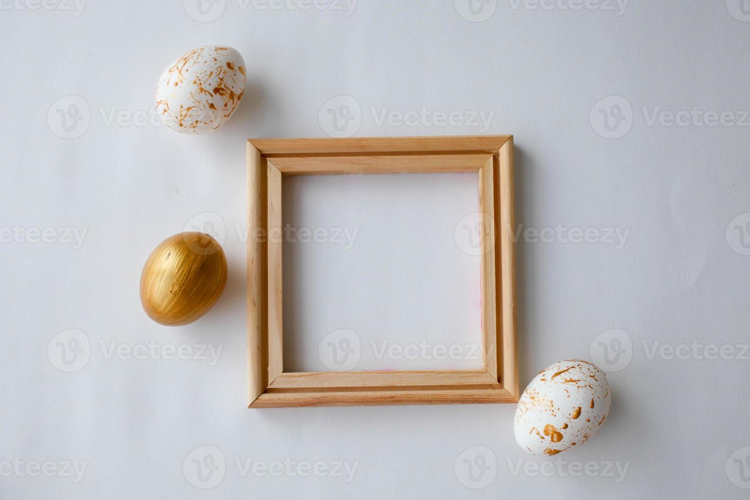 Pasqua uova su un' oro e di legno telaio sfondo su un' bianca sfondo. foto