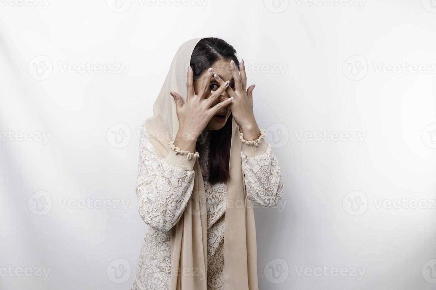 divertente ovvio sbirciando asiatico musulmano donna indossare foulard isolato su bianca sfondo. foto