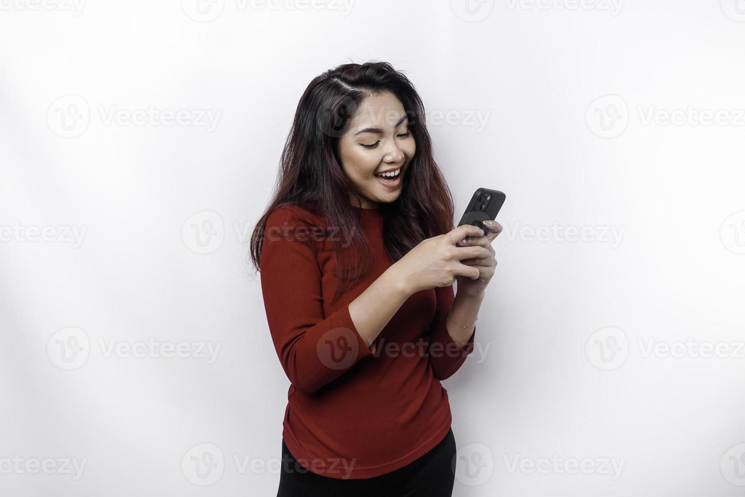 un' ritratto di un' contento asiatico donna vestito nel rosso e Tenere sua Telefono, isolato di bianca sfondo foto