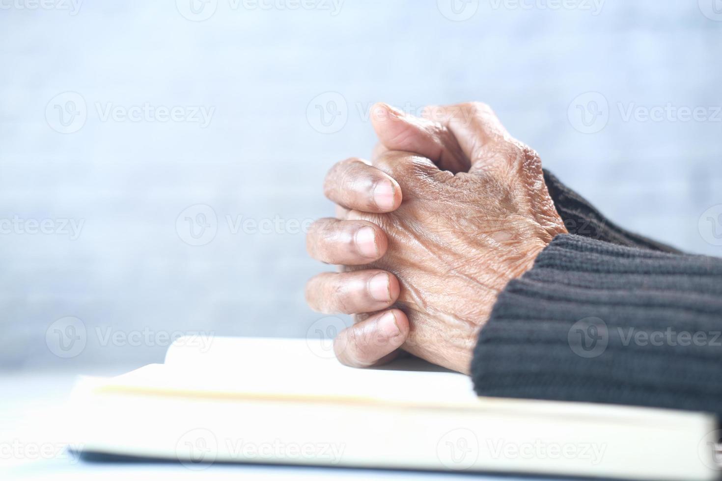 mani della donna che pregano su un libro foto