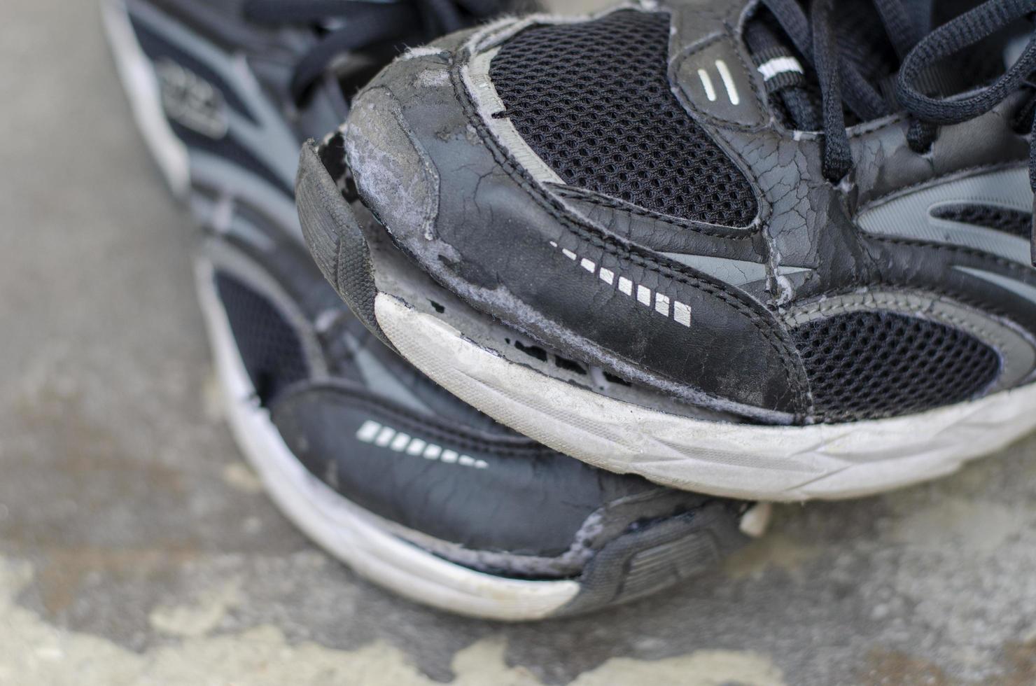 vicino su. rotto vecchio nero scarpe su il pavimento foto