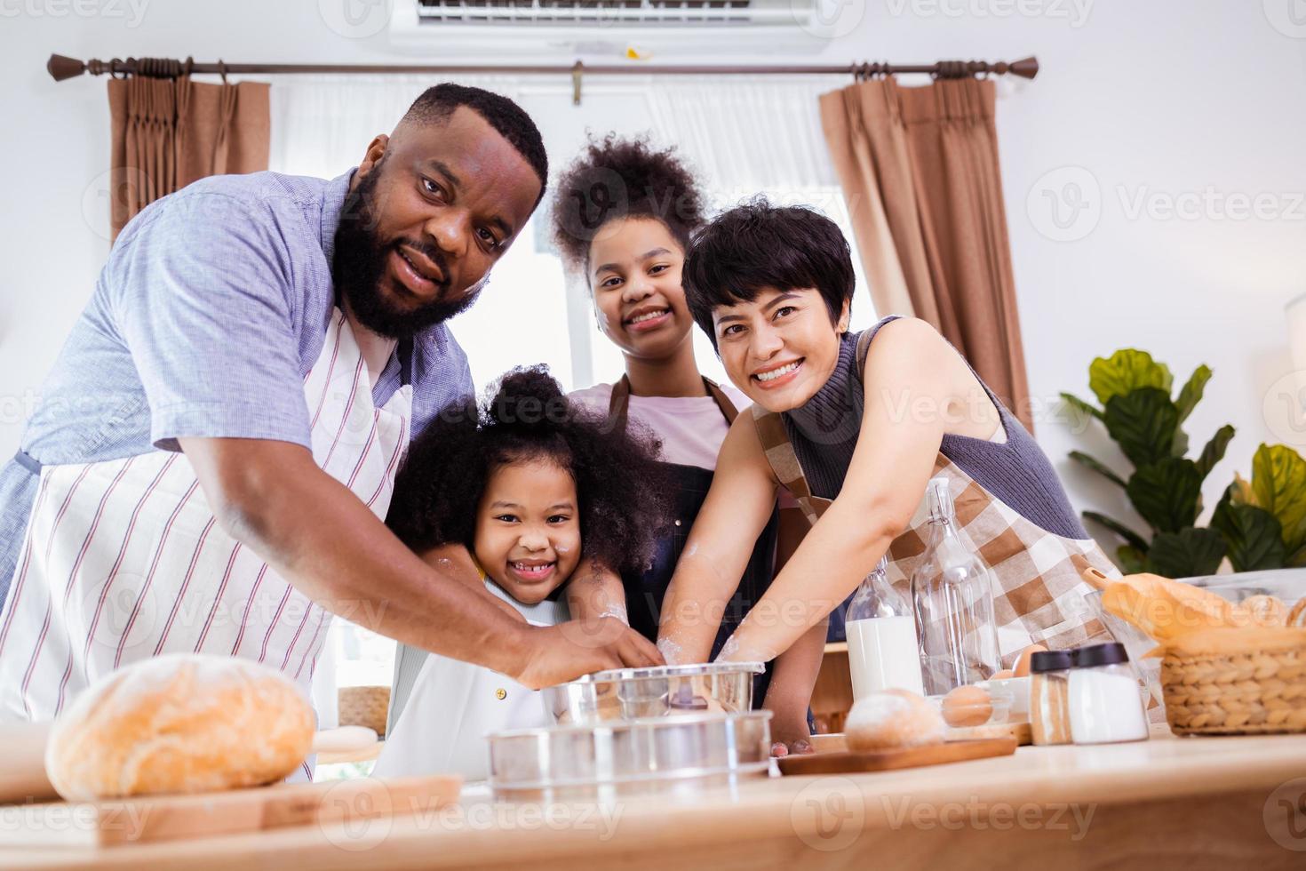 contento africano americano famiglia godere insieme mentre preparare il Farina per fabbricazione biscotti a casa foto