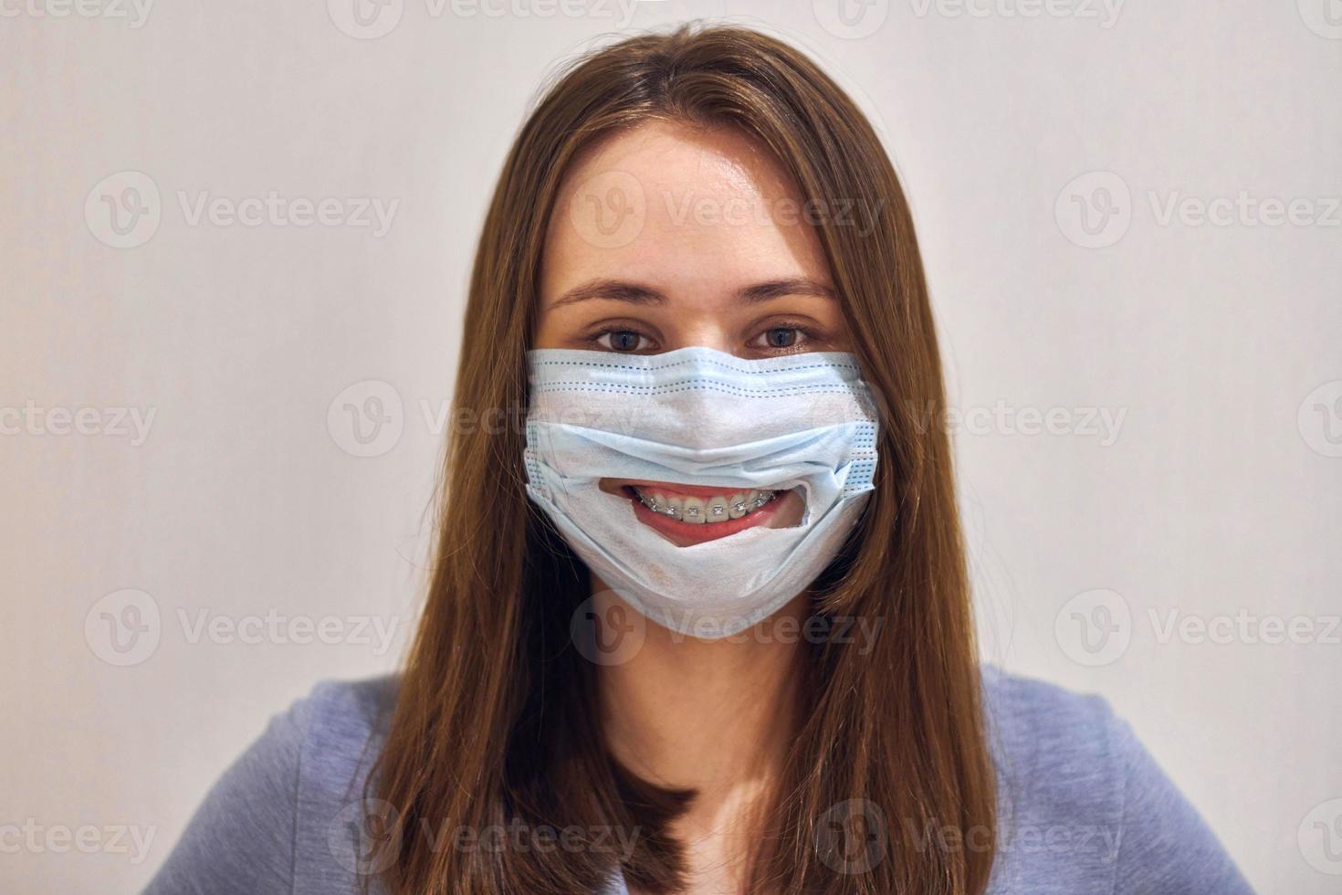 divertente sorridente ragazza con dentale bretelle indossare chirurgico maschera. foto
