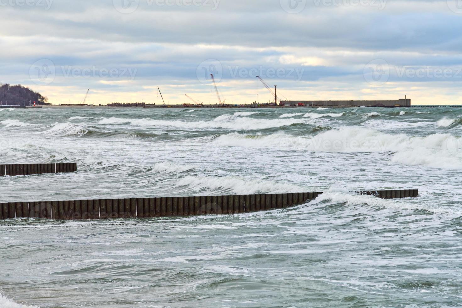 vista del mare blu con onde spumeggianti e frangiflutti in legno foto