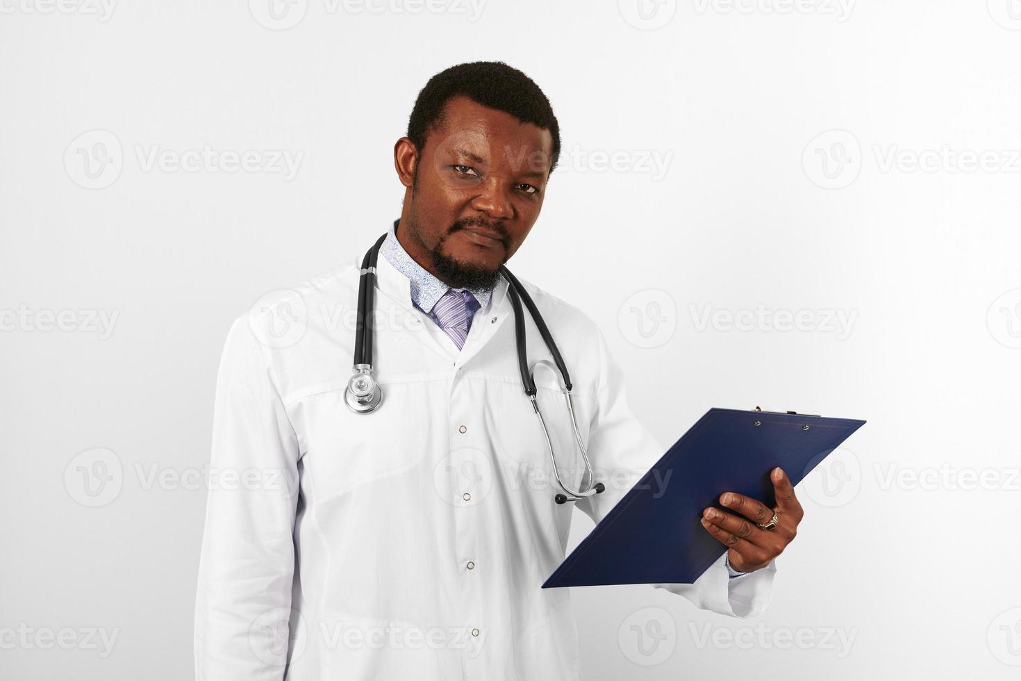 nero barbuto medico uomo nel bianca accappatoio con stetoscopio detiene medico grafico su appunti foto