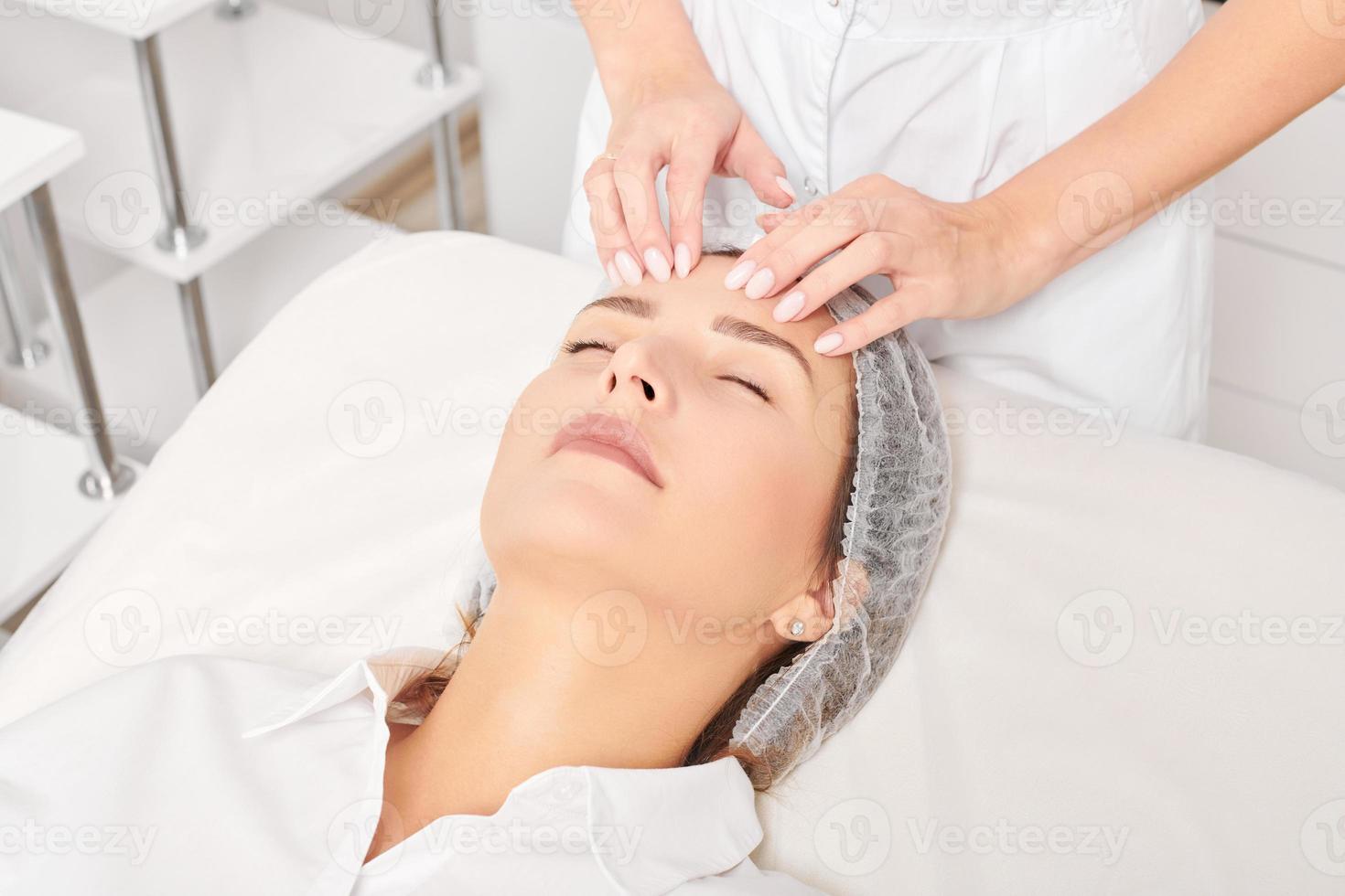 estetista massaggi donna viso pelle dopo sfregamento idratante crema per ringiovanimento nel clinica foto