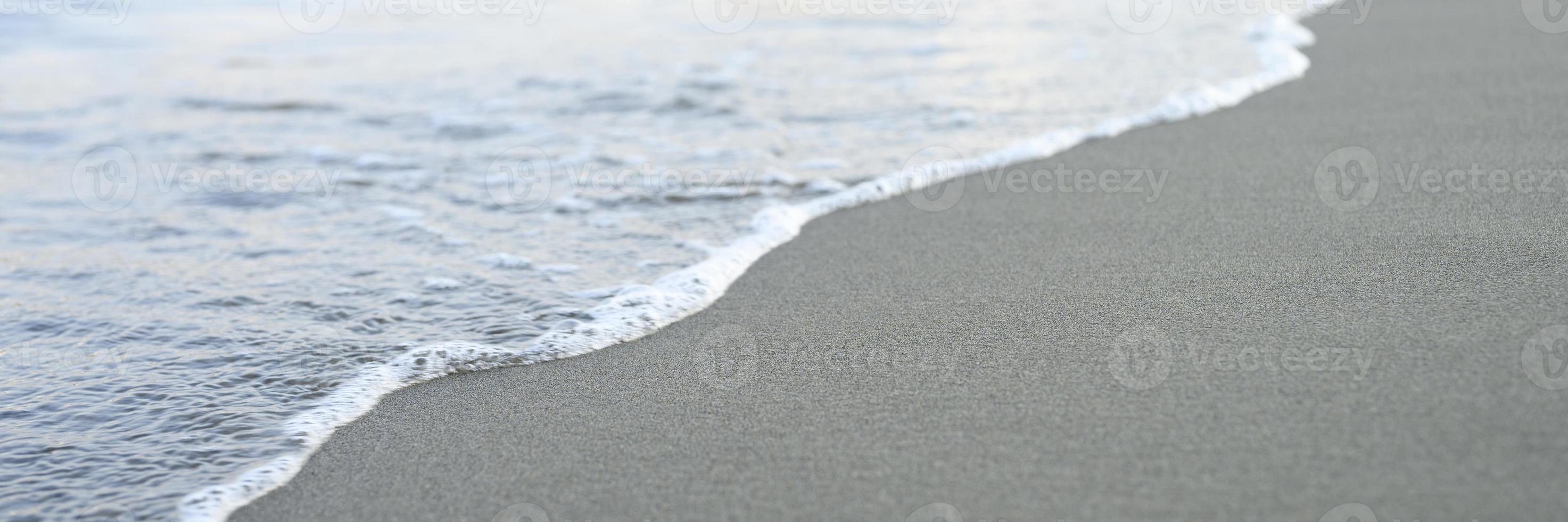 onda sfocata del mare sulla spiaggia di sabbia di sera foto