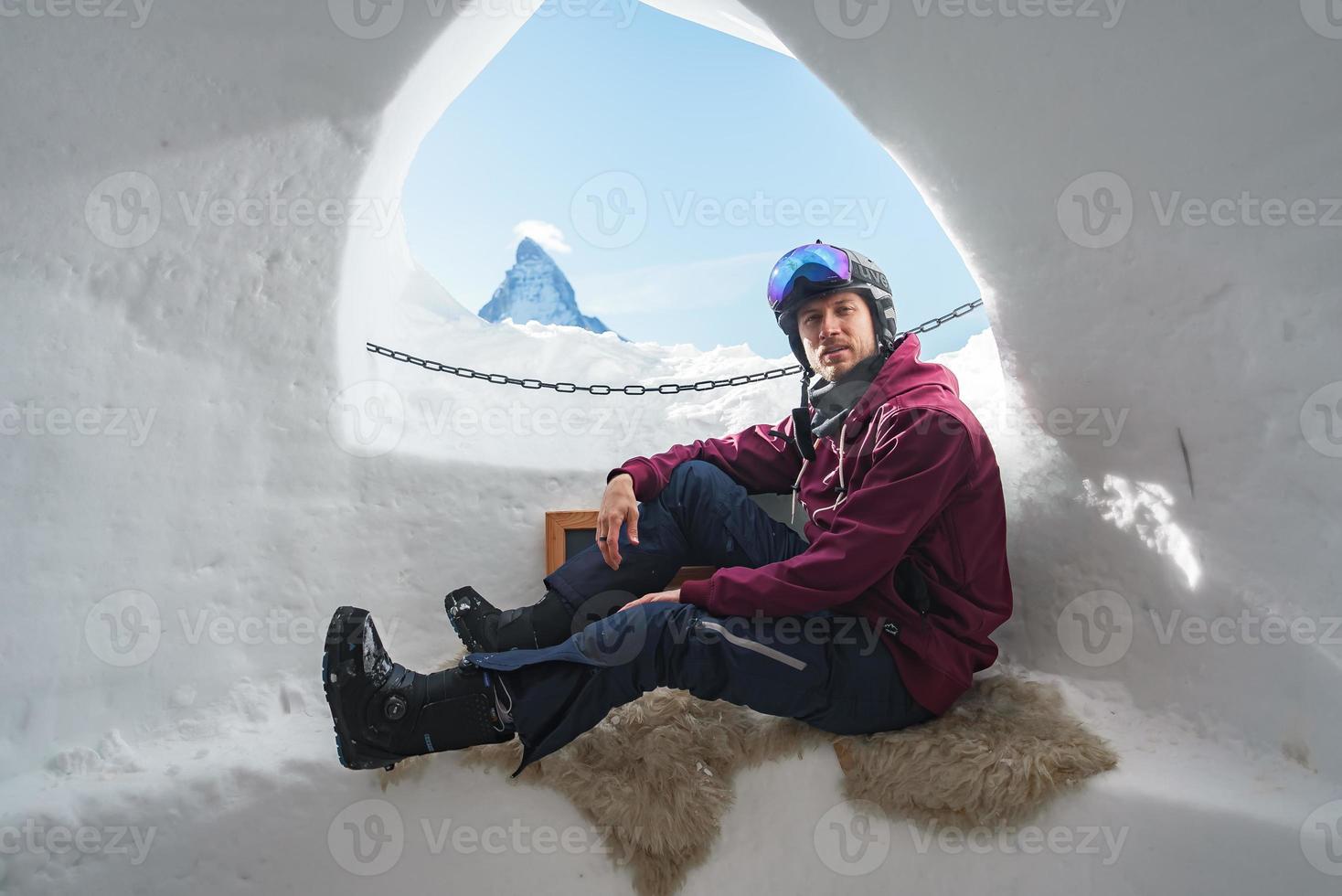 ritratto di sorridente turista snowboarder seduta dentro un iglu dorf con un' Visualizza su il famoso Innevato Cervino montagna. rilassante nel svizzero Alpi, Zermatt sciare ricorrere. foto