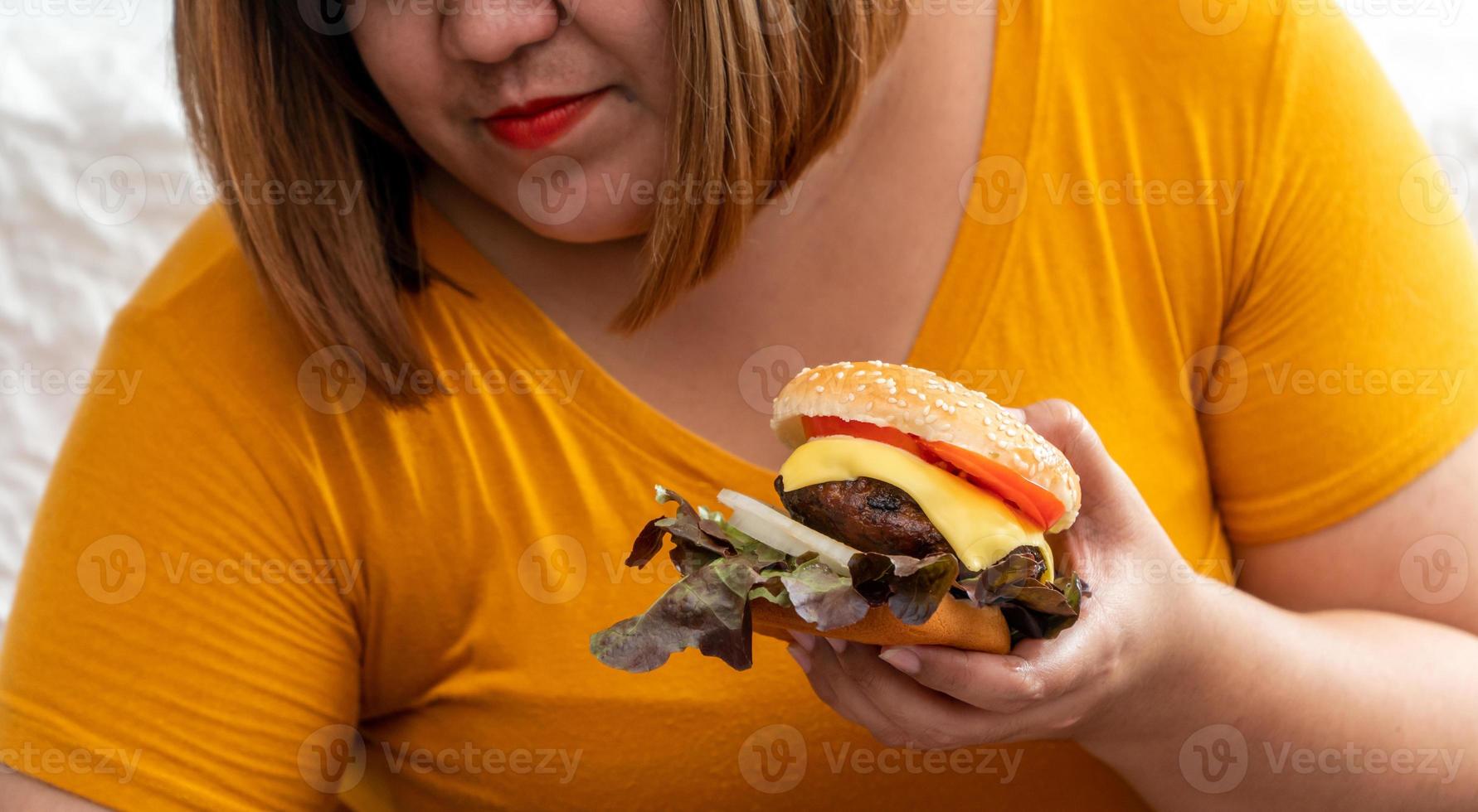 Affamato sovrappeso giovane asiatico donna Tenere Hamburger, sua Affamato tutti tempo e mangiare troppo, golosità e abbuffata mangiare. sua stile di vita è mangiare veloce cibo tutti volta. malsano concetto foto