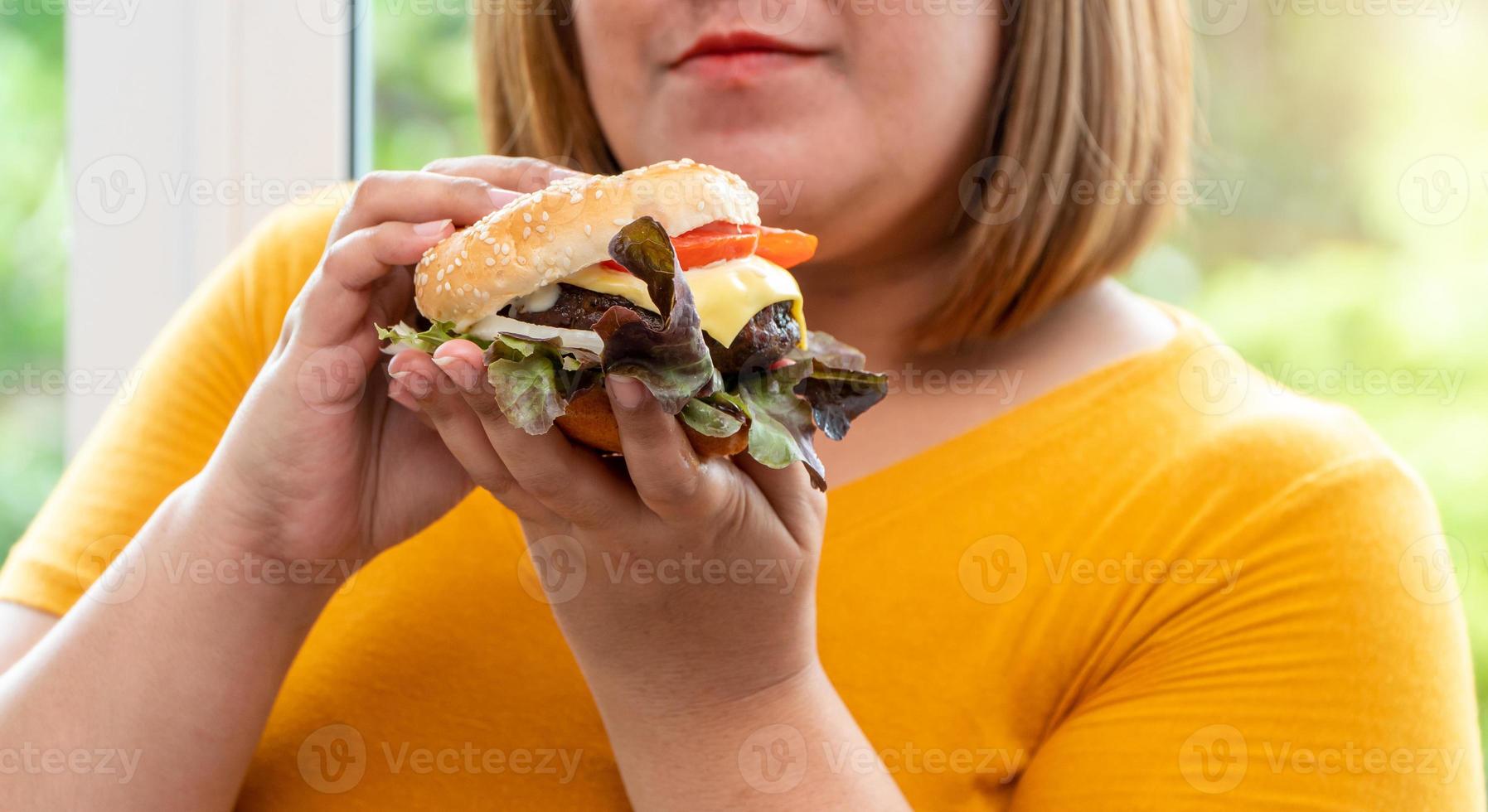 Affamato sovrappeso giovane asiatico donna Tenere Hamburger, sua Affamato tutti tempo e mangiare troppo, golosità e abbuffata mangiare. sua stile di vita è mangiare veloce cibo tutti volta. malsano concetto foto