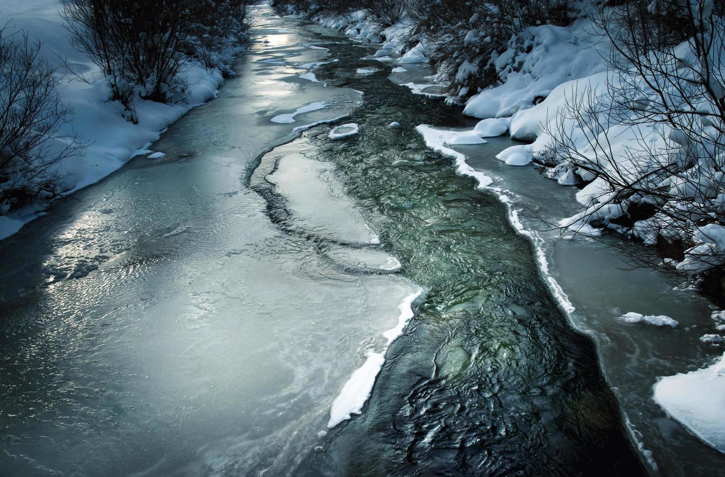 scena invernale buia con un fiume ghiacciato foto