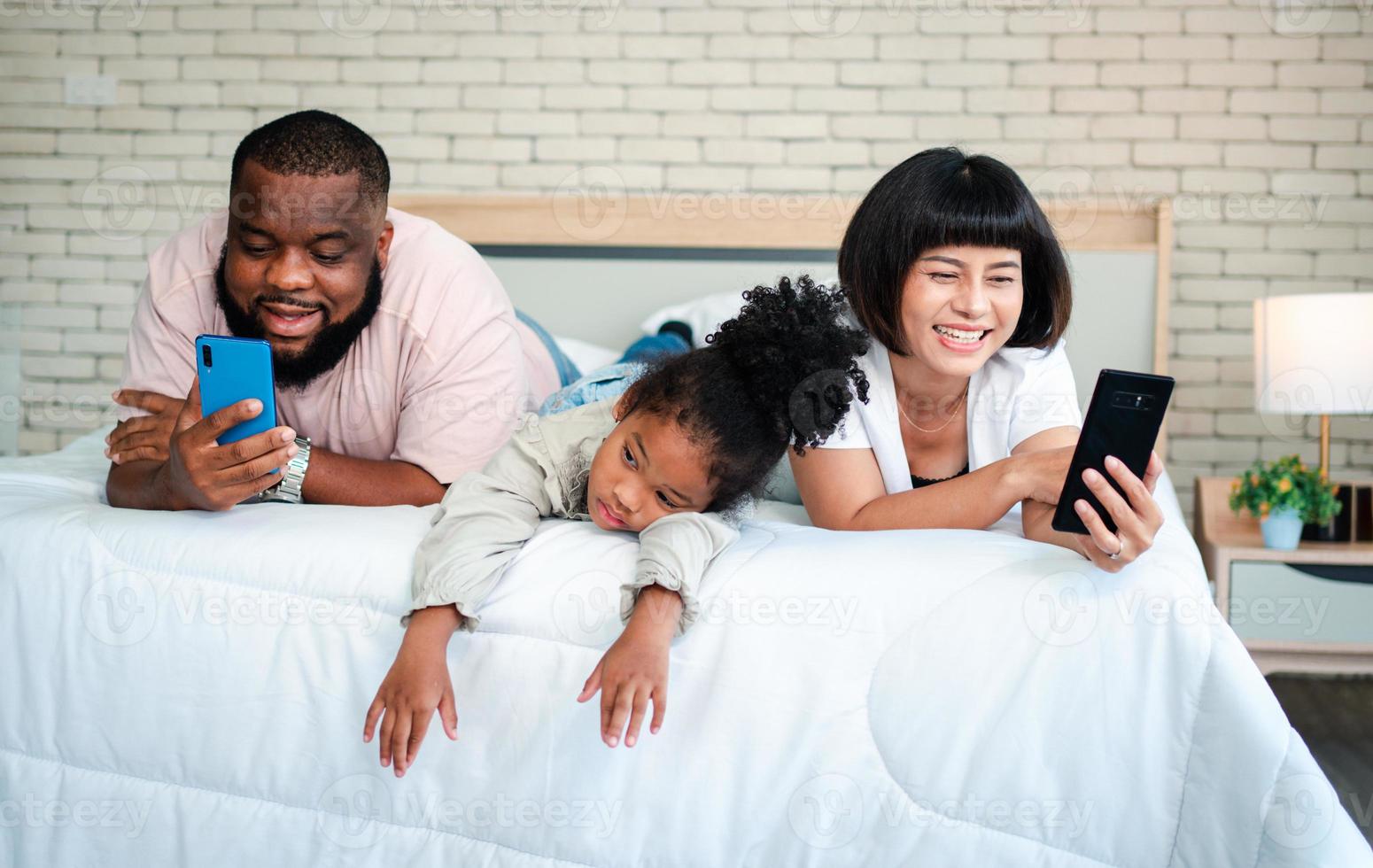 le ragazze afroamericane non sono soddisfatte e tristi, sedute in mezzo tra padre e madre. i genitori usano lo smartphone e i bambini abbandonati. i bambini hanno bisogno dell'attenzione dei genitori. foto
