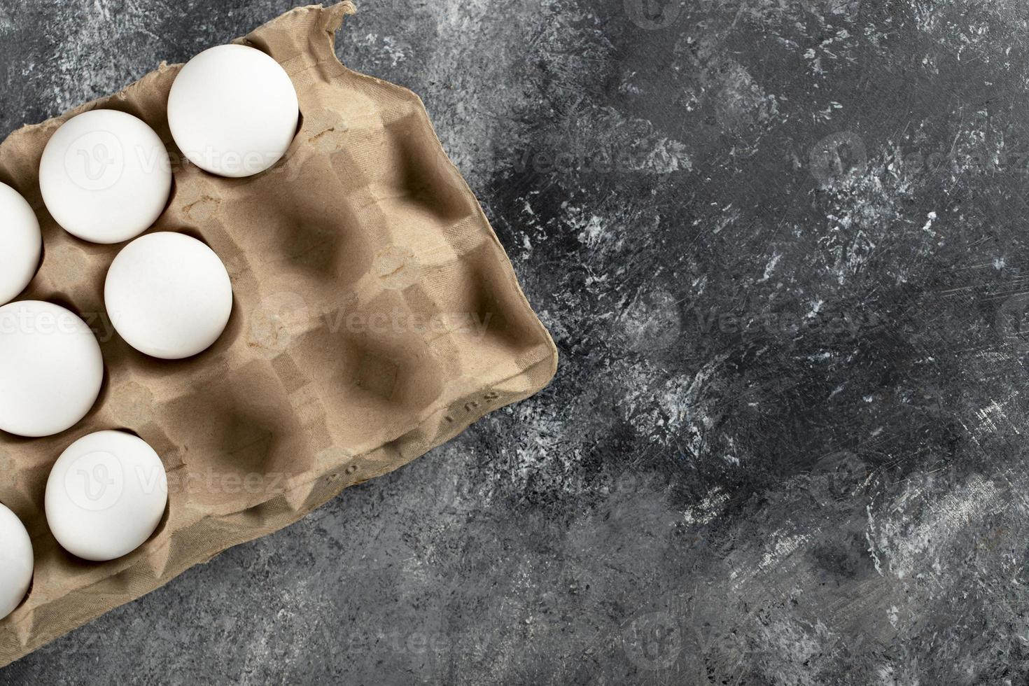 uova di gallina crude in una scatola per uova su uno sfondo di marmo foto